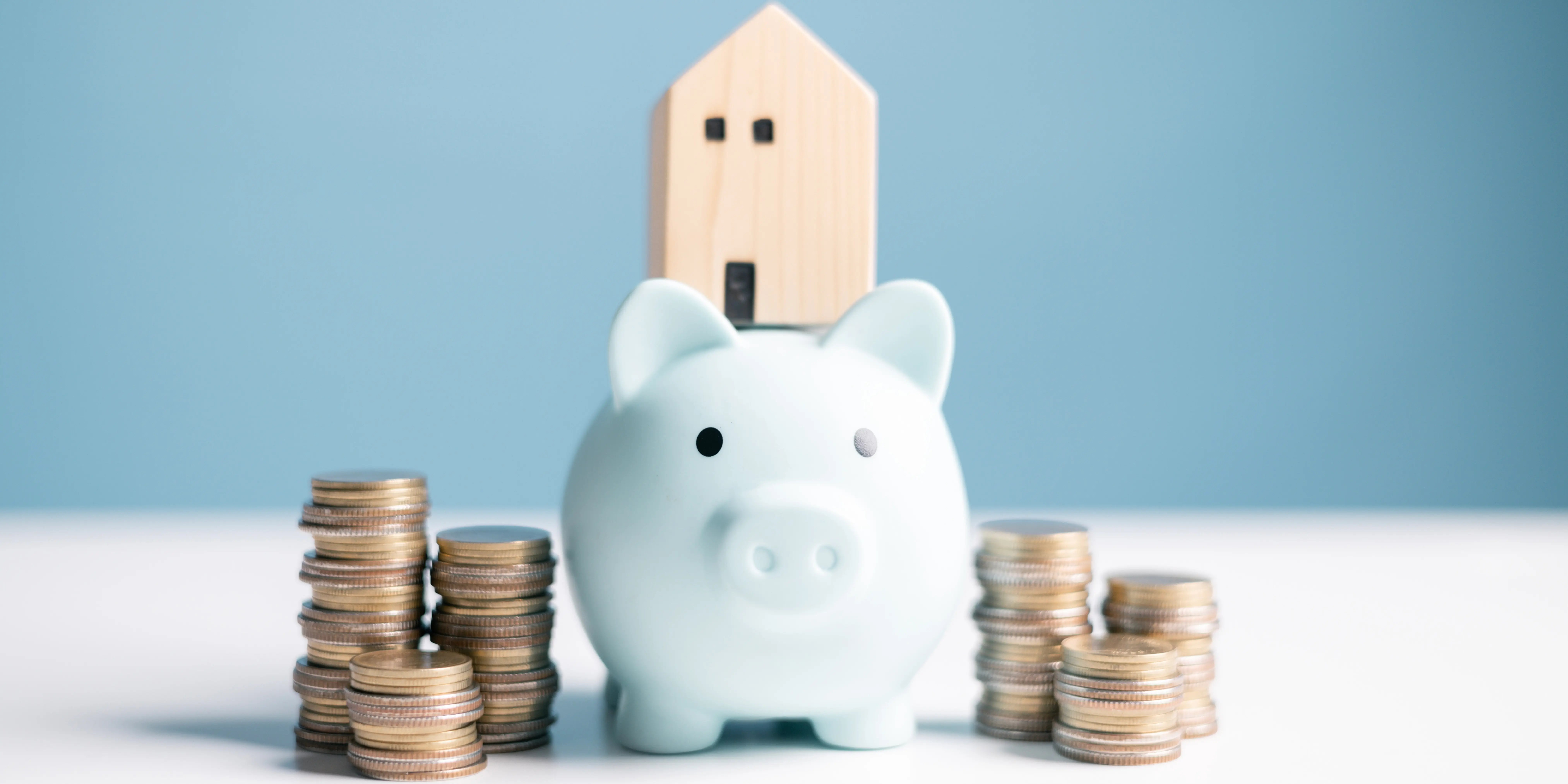 Alcancía con torres de monedas a los lados y una casa de madera encima