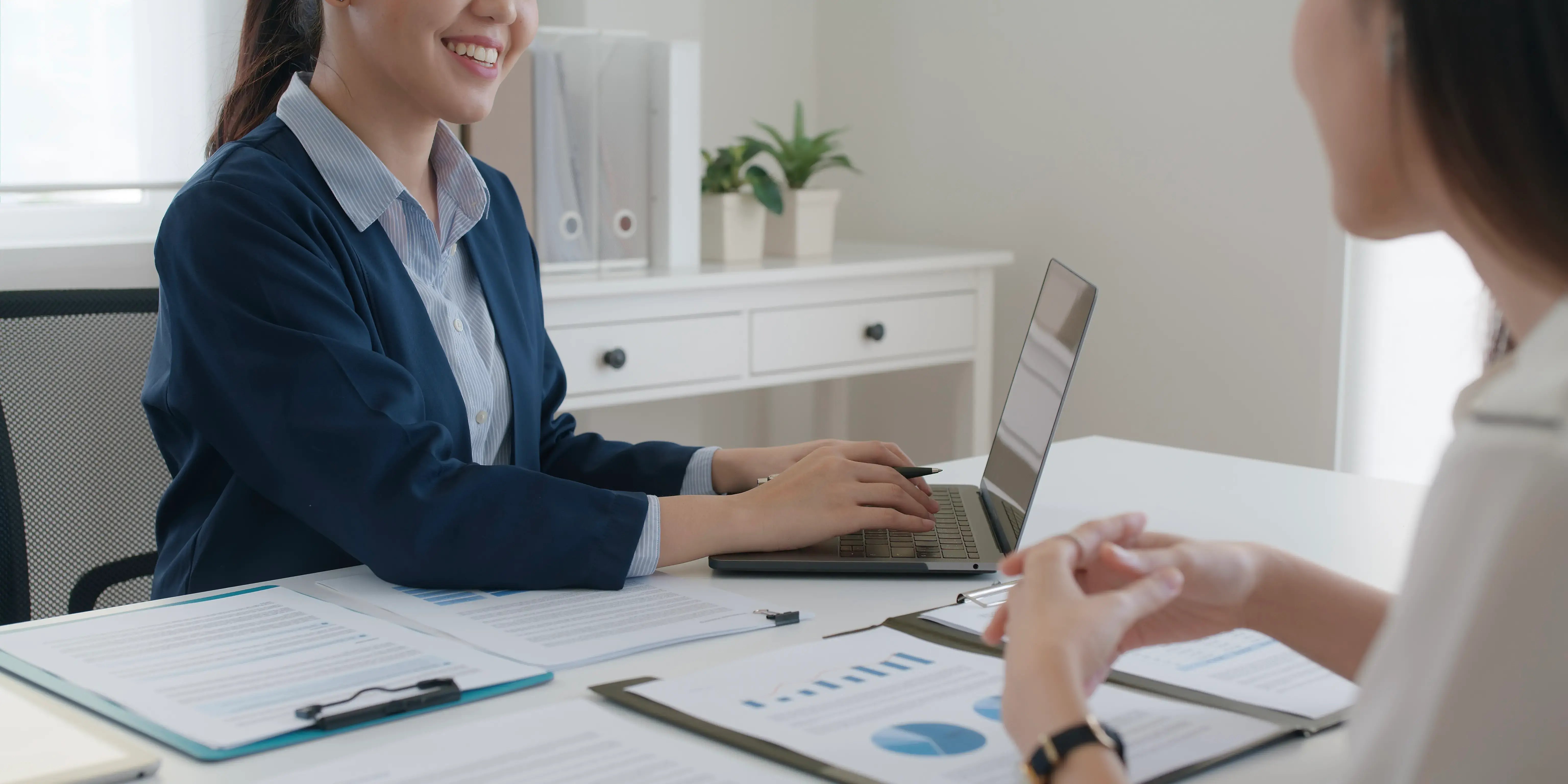 Asesor financiero en el banco utilizando una computadora y explicando al cliente los términos de tasa de interés, CAT y comisiones para comprar casa sin usar Infonavit