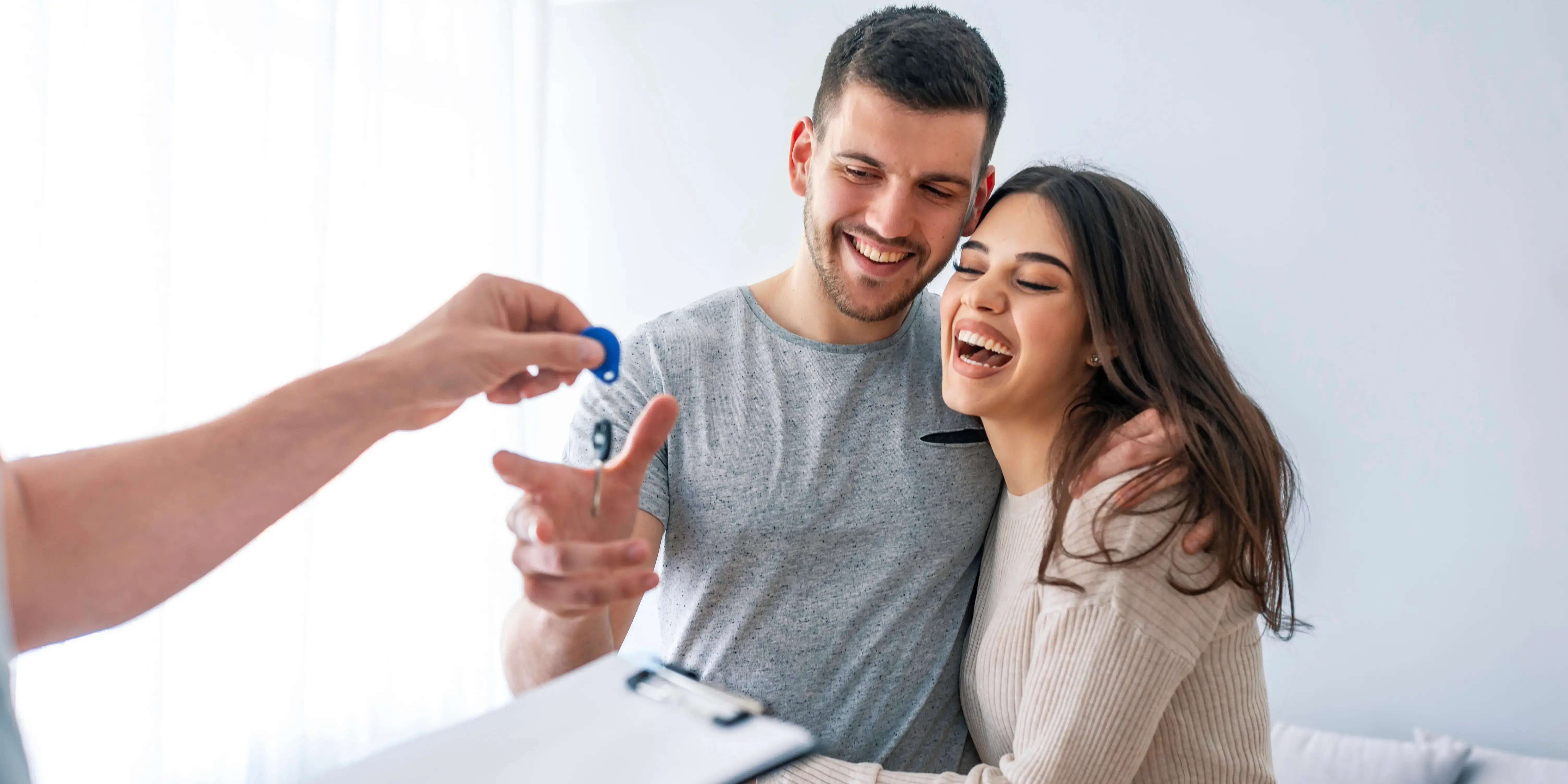 Asesor inmobiliario entregando las llaves de su nueva casa a una pareja feliz y sonriente que la compraron sin usar Infonavit