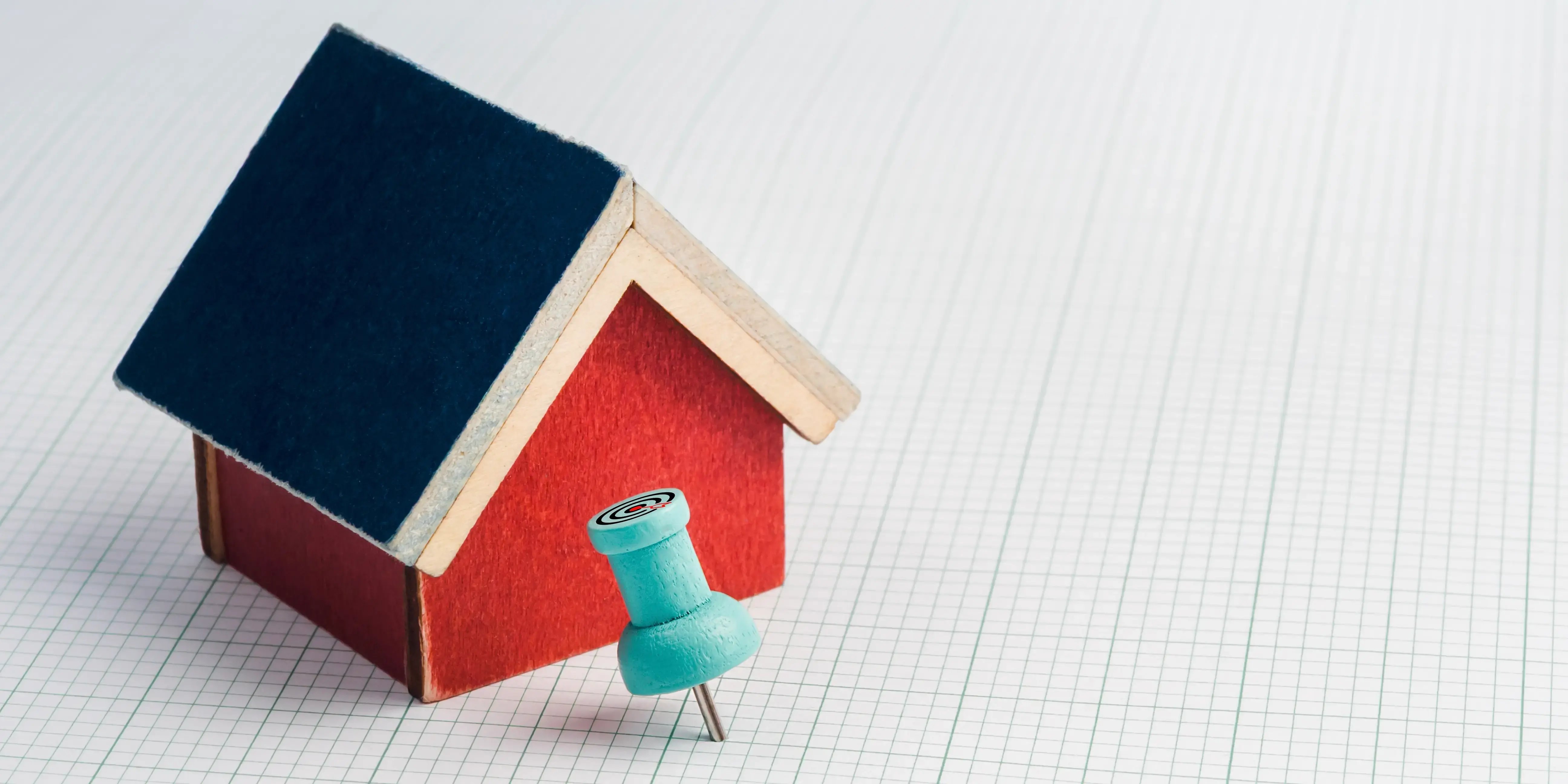Casa de madera con un pin para elegir la mejor ubicación para comprar casa o departamento