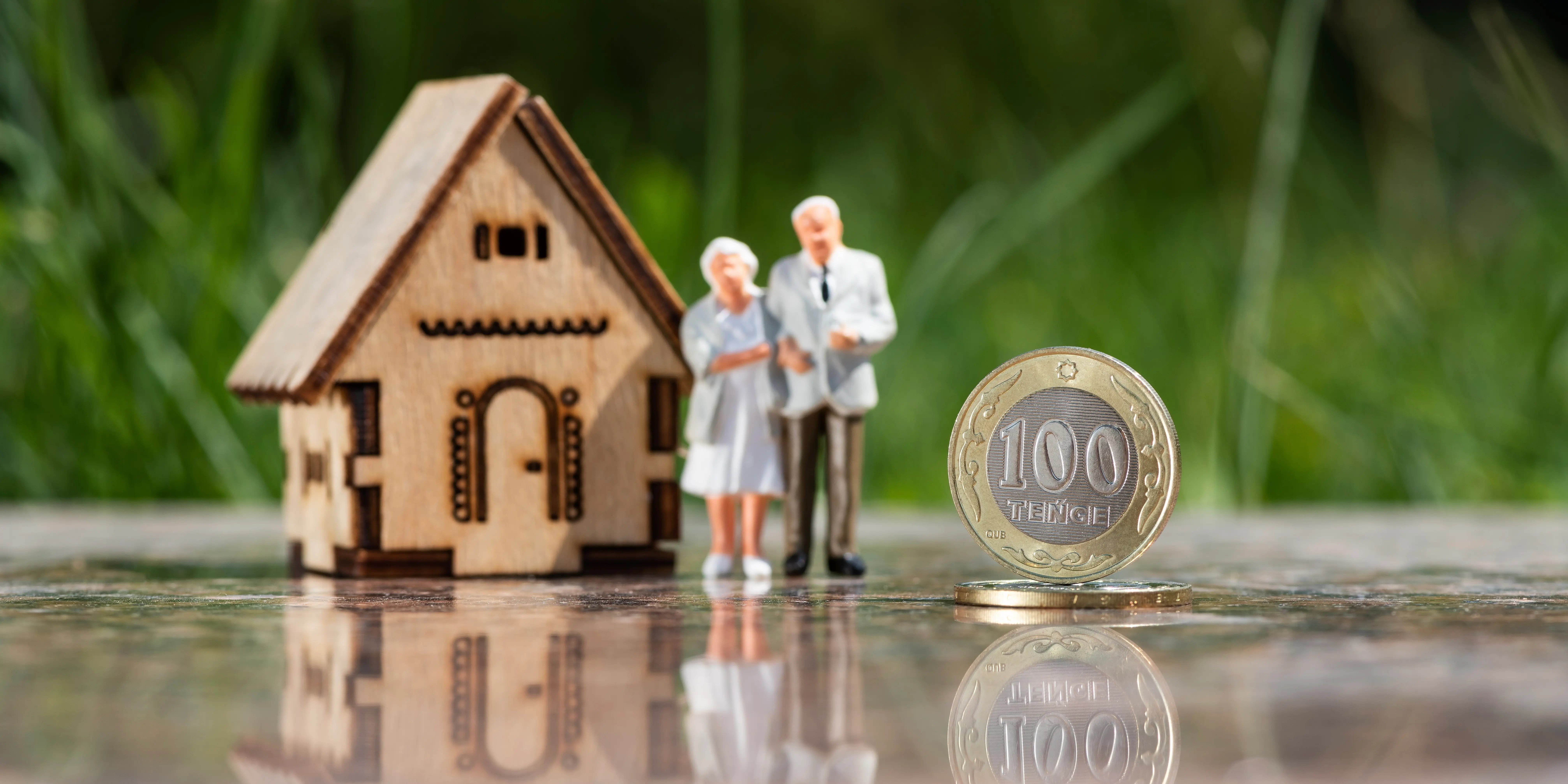 Casa de madera junto con unas figuras de personas mayores y una moneda como ejemplo del dinero que te puede prestar el crédito hipotecario IMSS