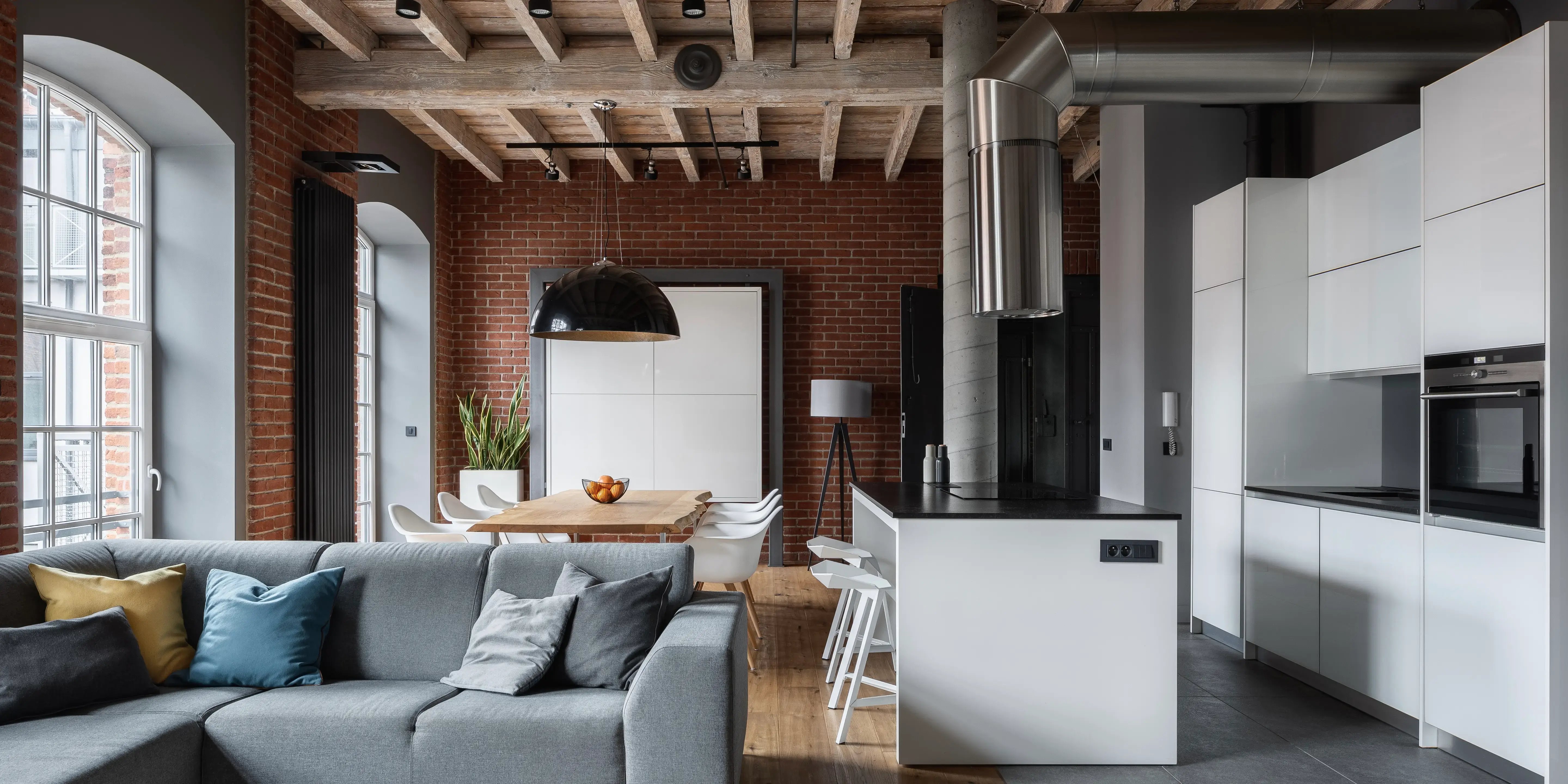 Cocina, sala y comedor con diseño de interiores estilo industrial con ladrillos y tuberías visibles