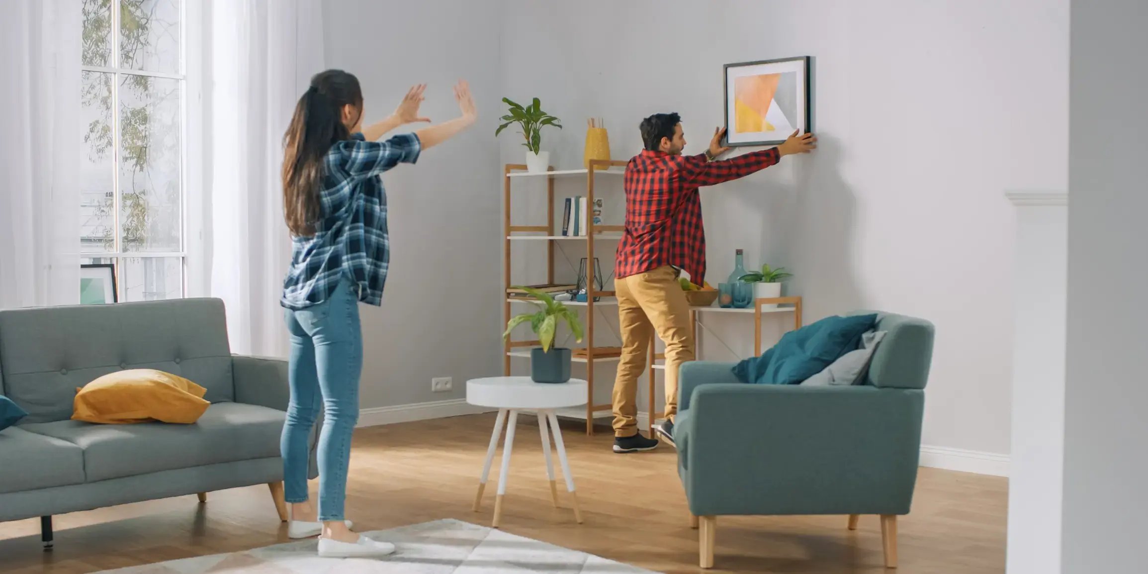 pareja en la sala colgando un cuadro. decoracion de interiores casas pequeñas