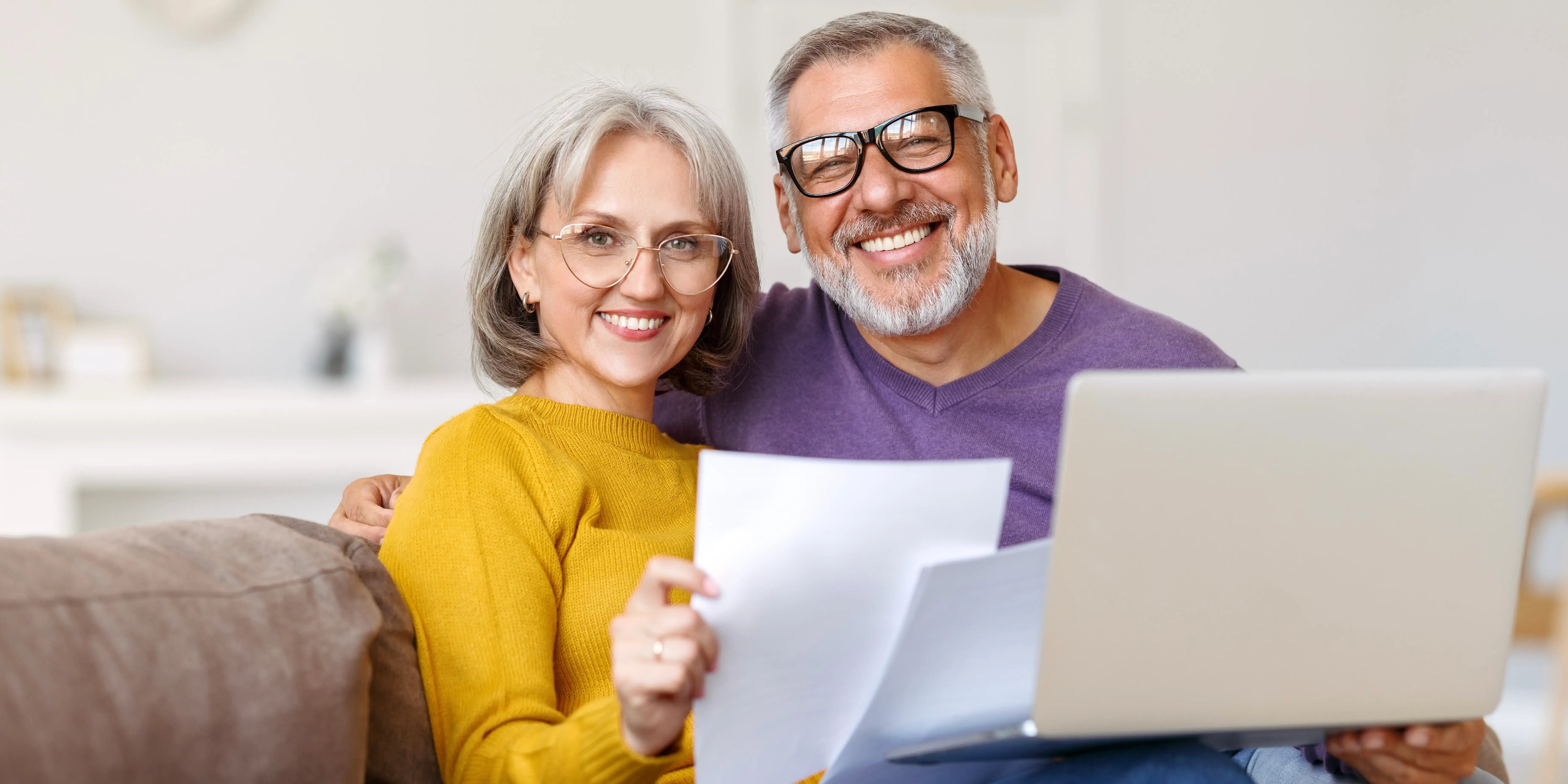 Feliz pareja mayor sosteniendo documentos financieros y leyendo buenas noticias en una carta de inversiones a largo plazo