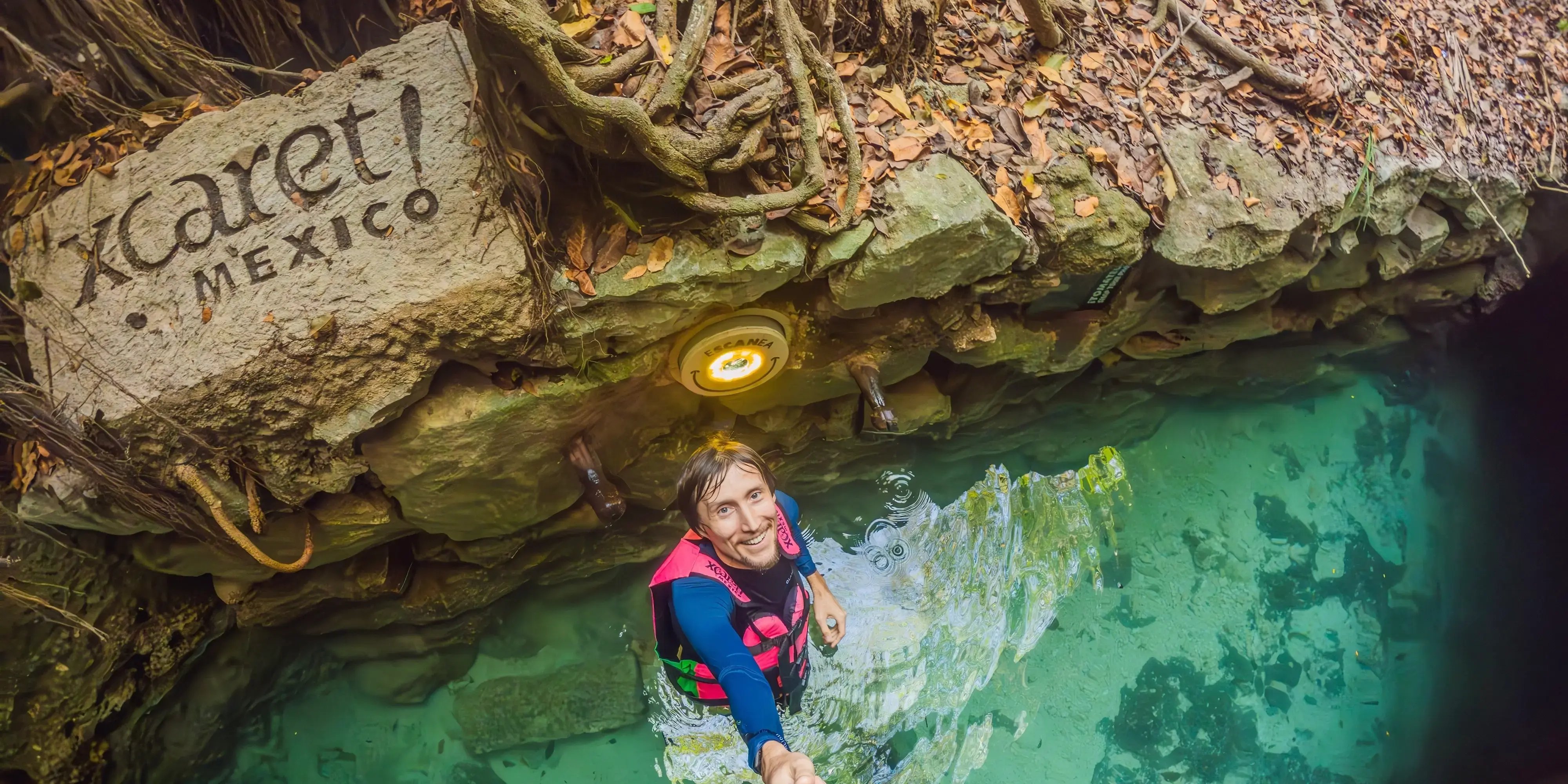 Hombre arado en el agua de un cenote en el parque Xcaret con un chaleco salvavidas