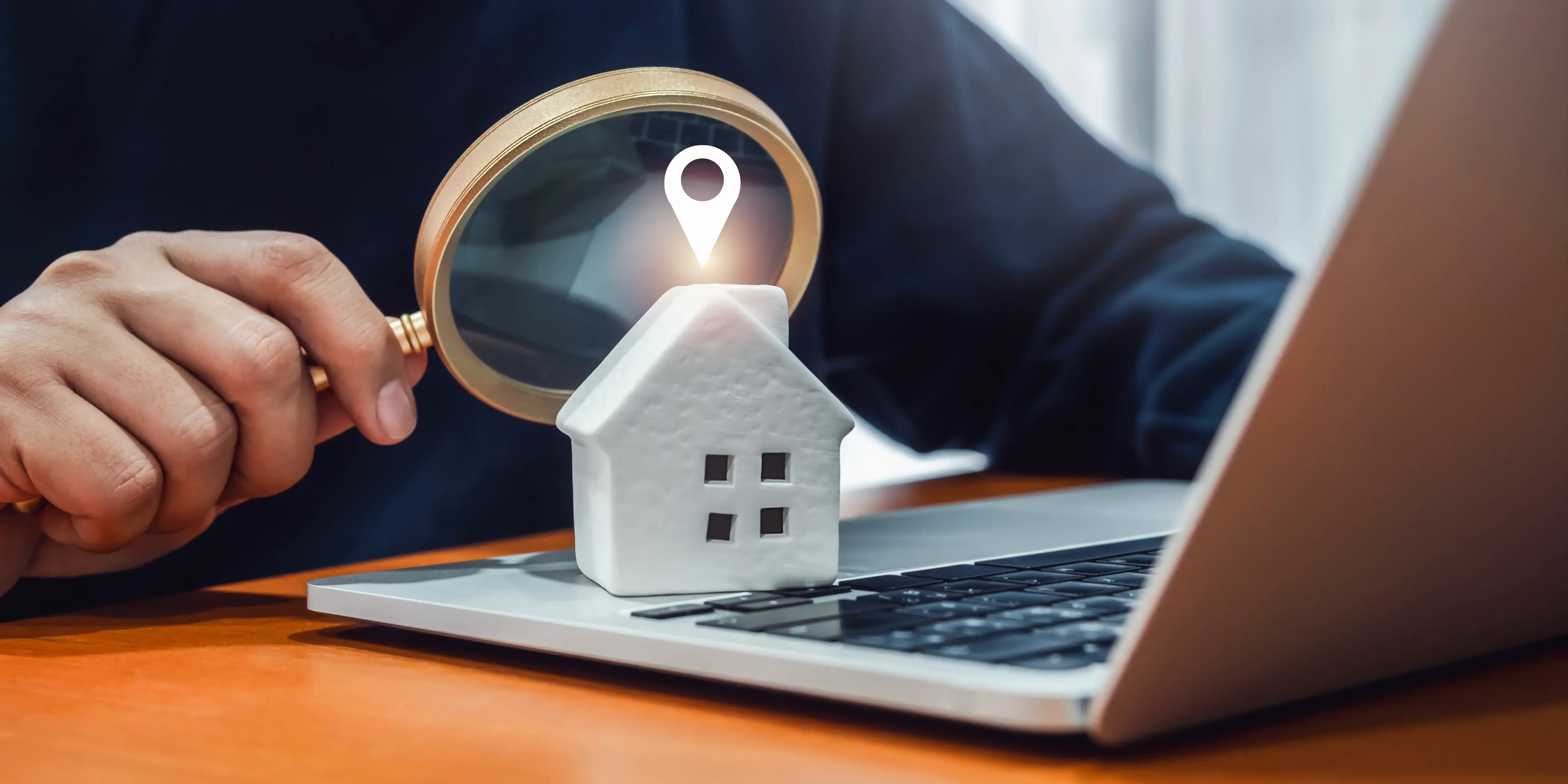 Hombre con una laptop y una lupa buscando la ubicación de una casa para conocer que lugares están cerca e invertir en bienes raíces en méxico