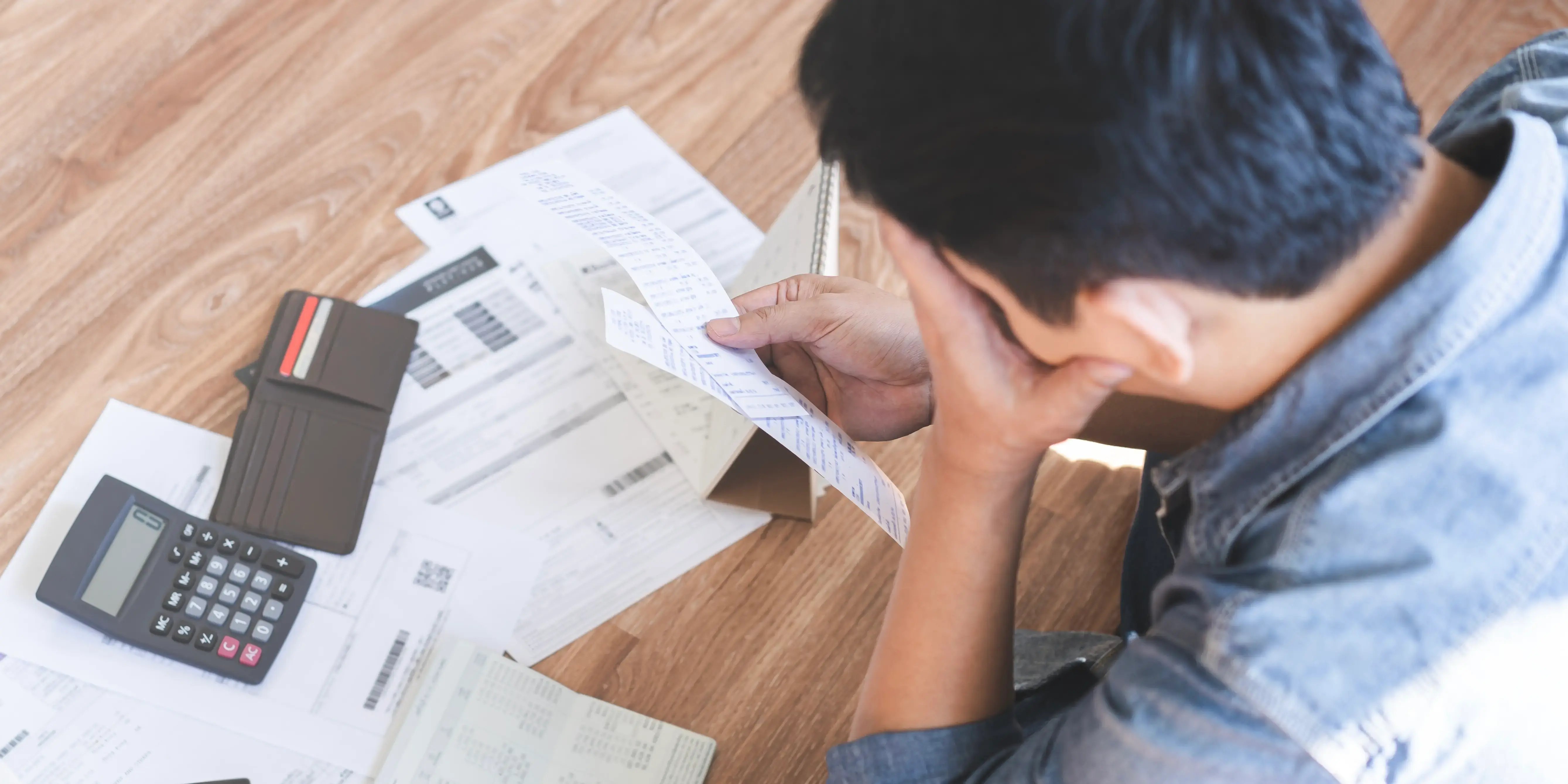 Hombre preocupado por solicitar un crédito bancario, revisando recibos que están sobre una mesa