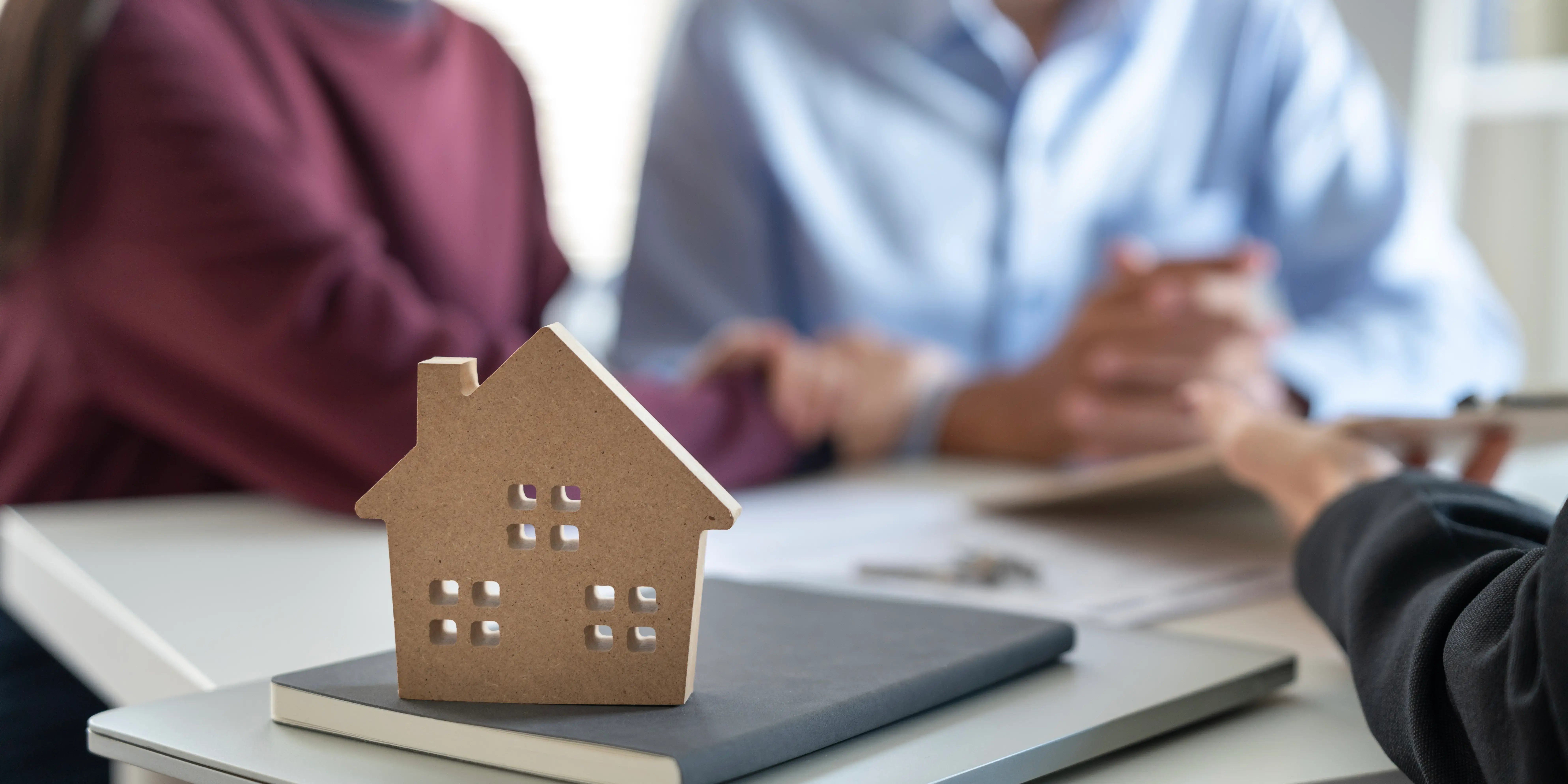 Joven pareja familiar habla con agente inmobiliario acerca del cofinavit para comprar casa sin dinero ahorrado