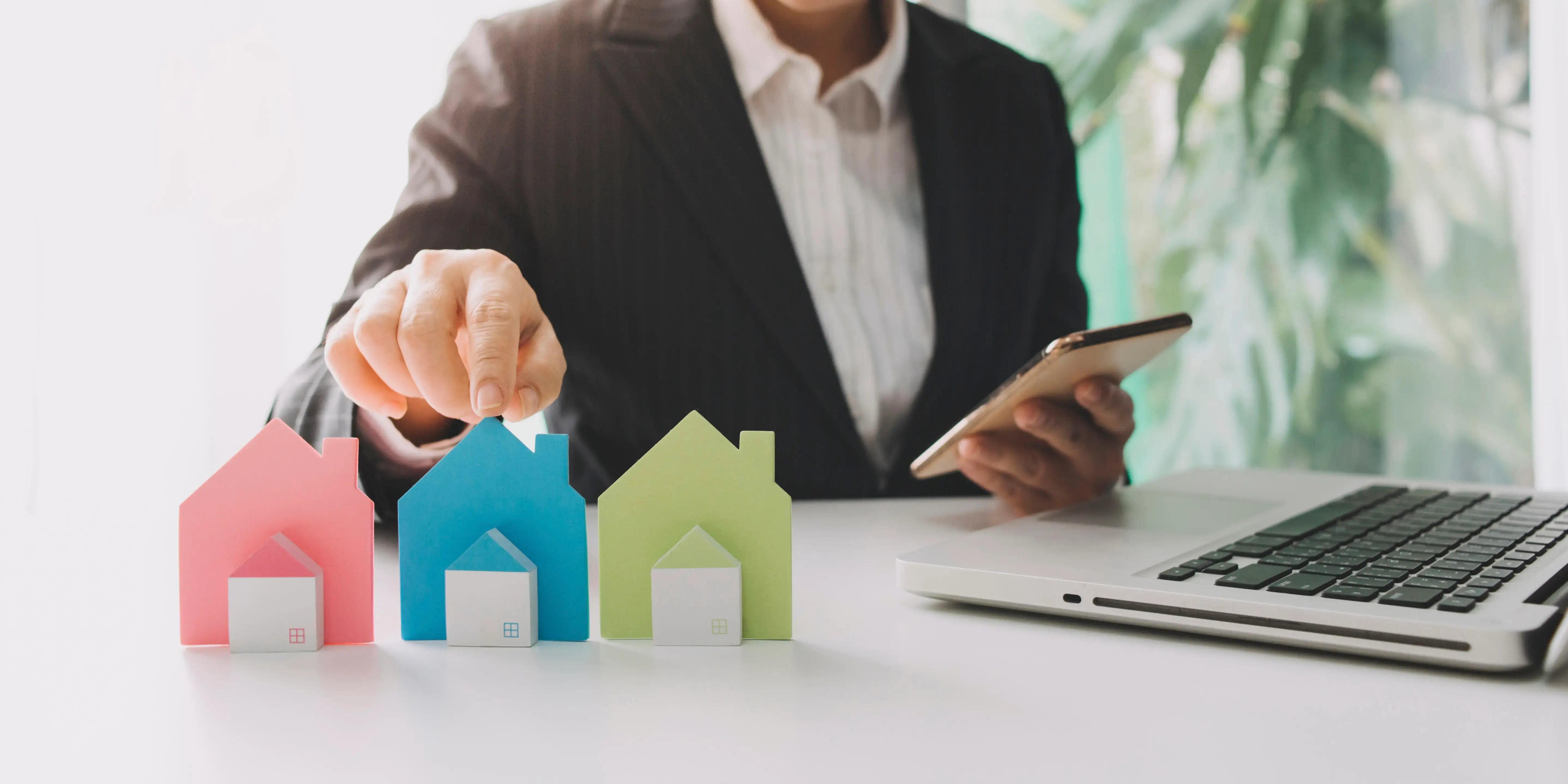 Mano hombre eligiendo mini modelo de casa de madera para elegir crédito infonavit, fovissste o bancario en los descuentos inmobiliarios