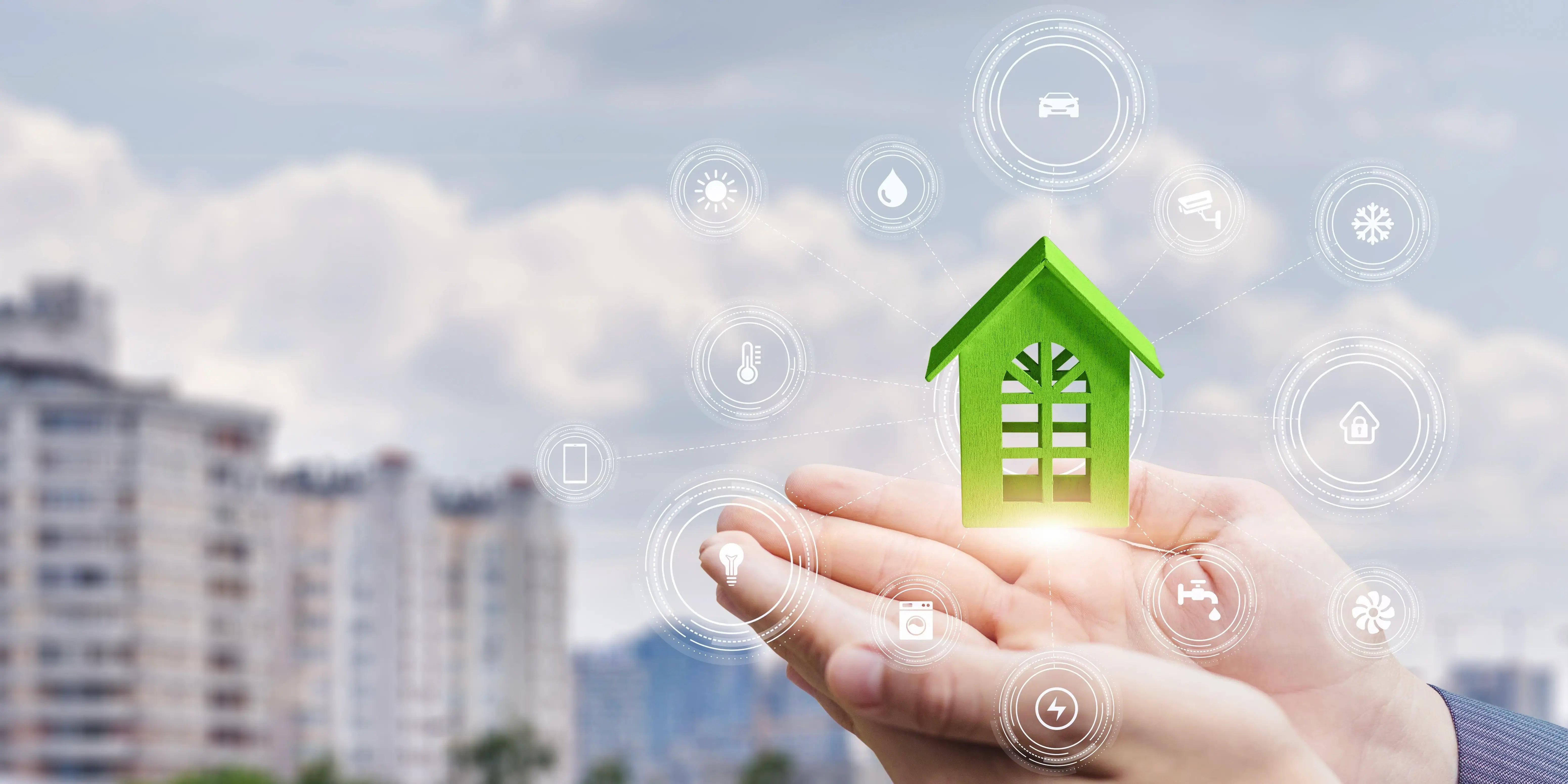 Manos sosteniendo una casa verde con íconos de lo que significa una casa con certificación edge y unos edificos al fondo