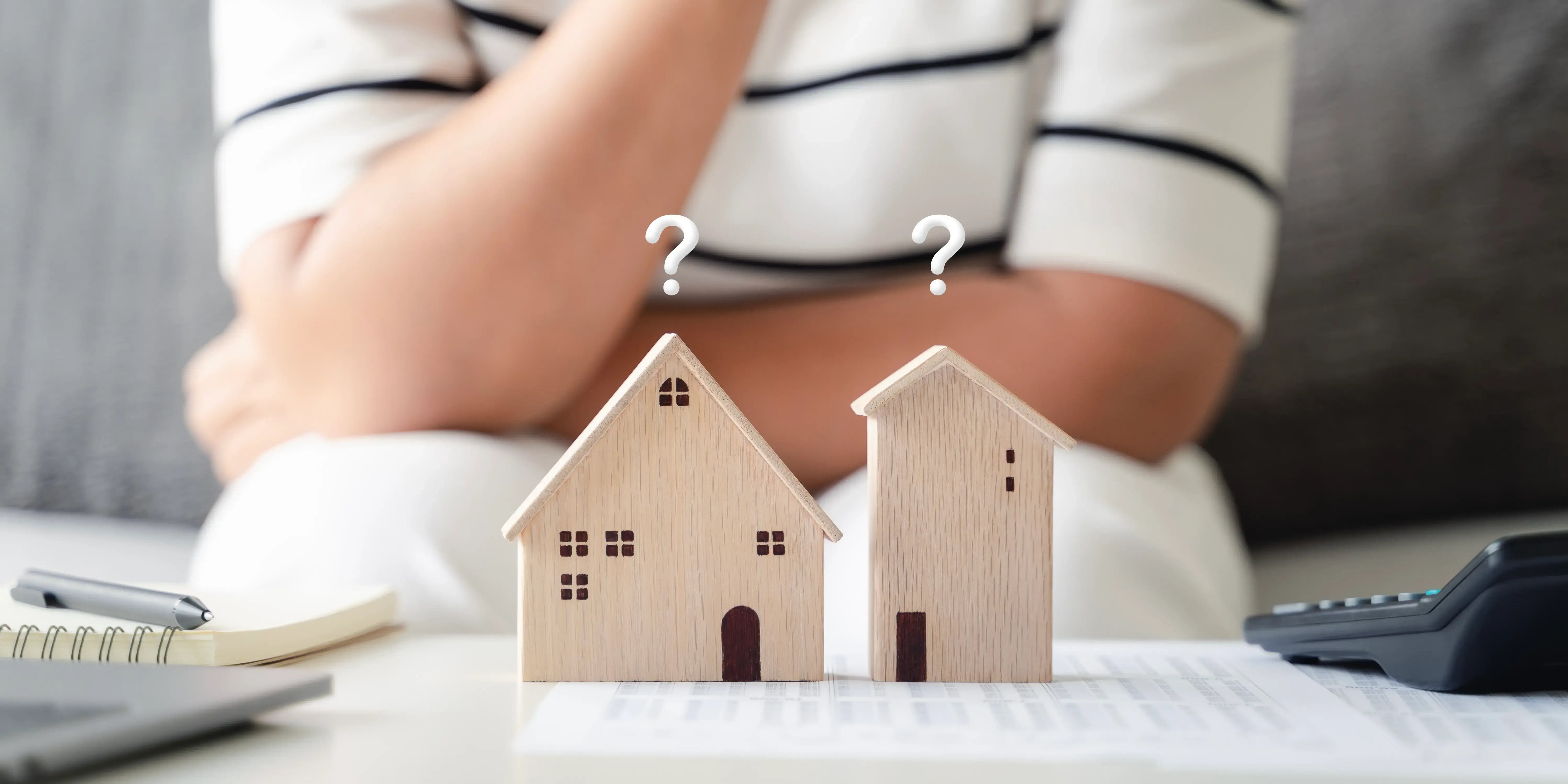 Mujer comparando entre 2 casas de madera de maqueta para elegir un crédito hipotecario de cuál le conviene más