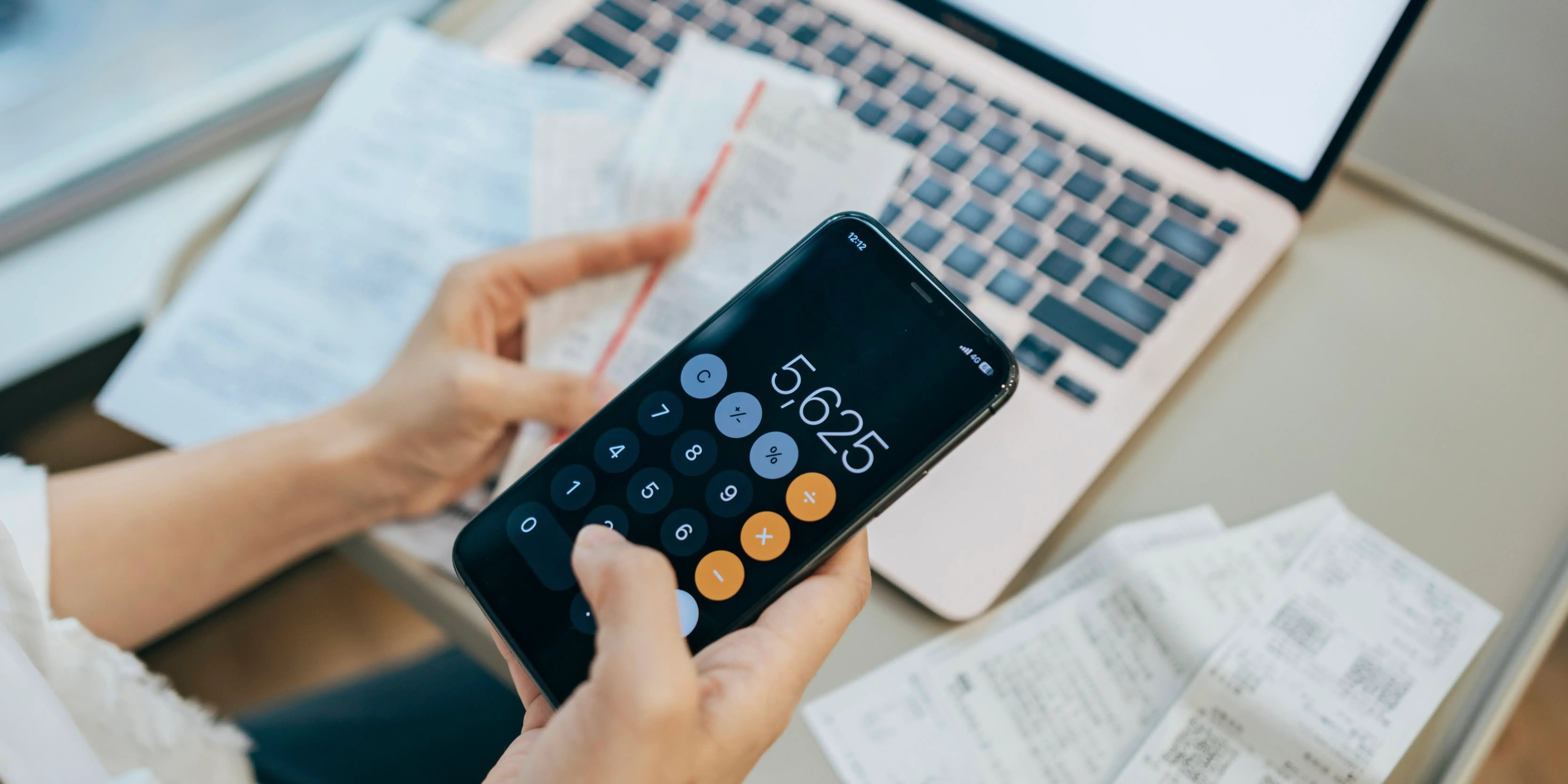 Mujer con un plan de presupuesto personal revisando tickets de compras y con el celular sacando cuentas de los gastos hormiga