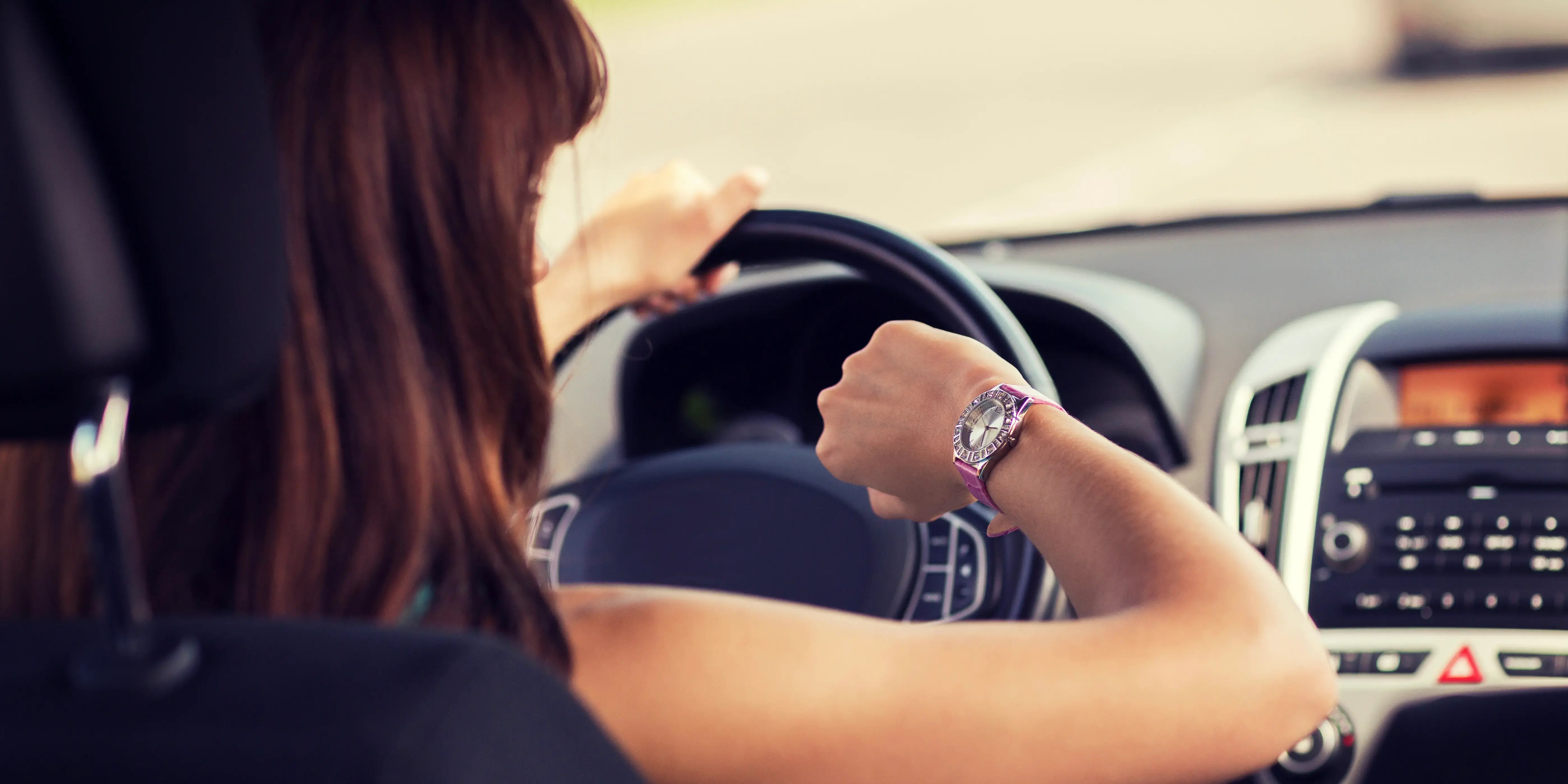 Mujer que conduce un coche y mira el reloj calculando los tiempos de traslado y elegir la mejor ubicación para comprar casa o departamento