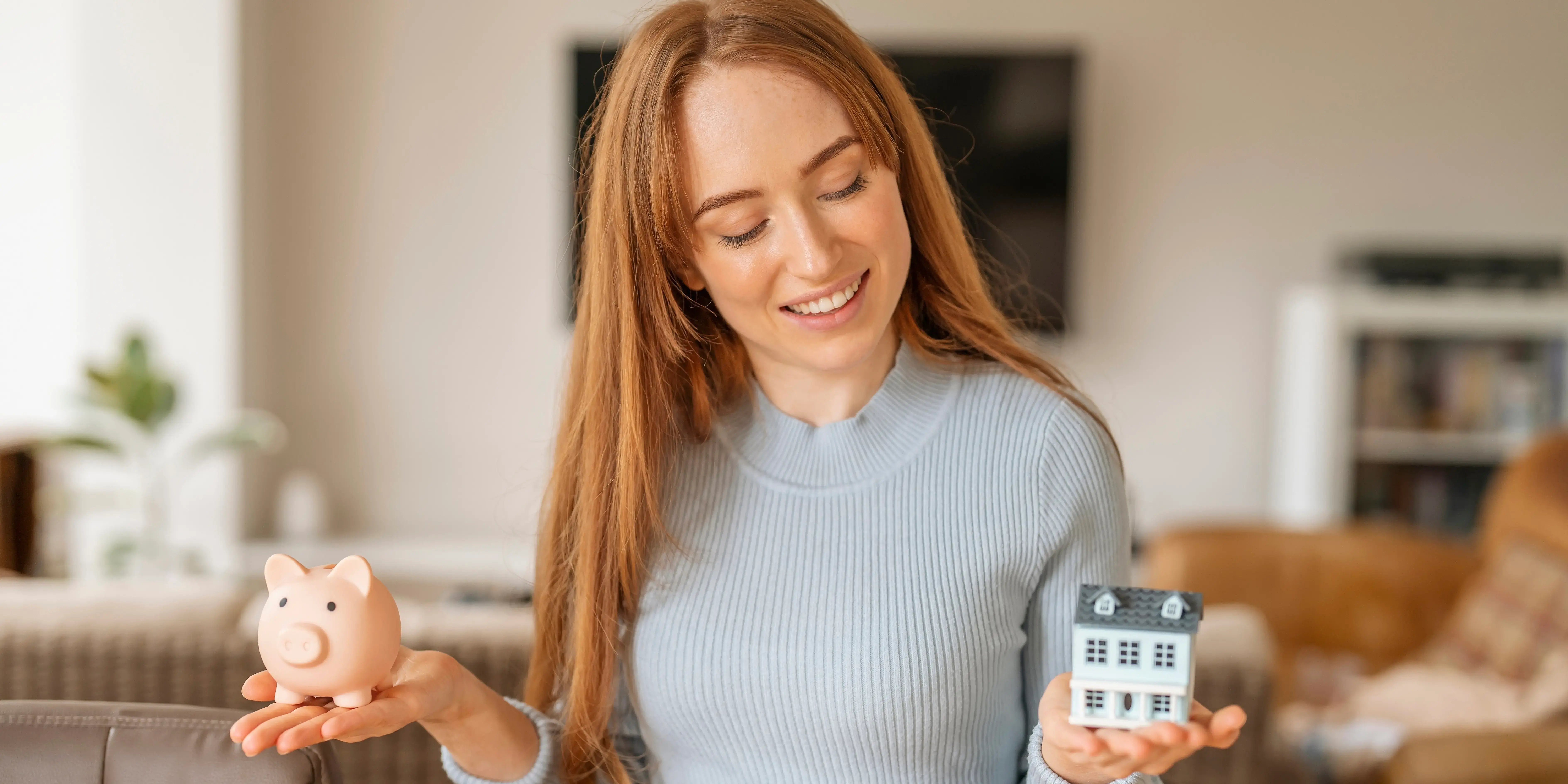 Mujer que tiene un plan de presupuesto personal y ahorra para comprar su casa. En una mano está sosteniendo una alcancía y en otra una casa de madera