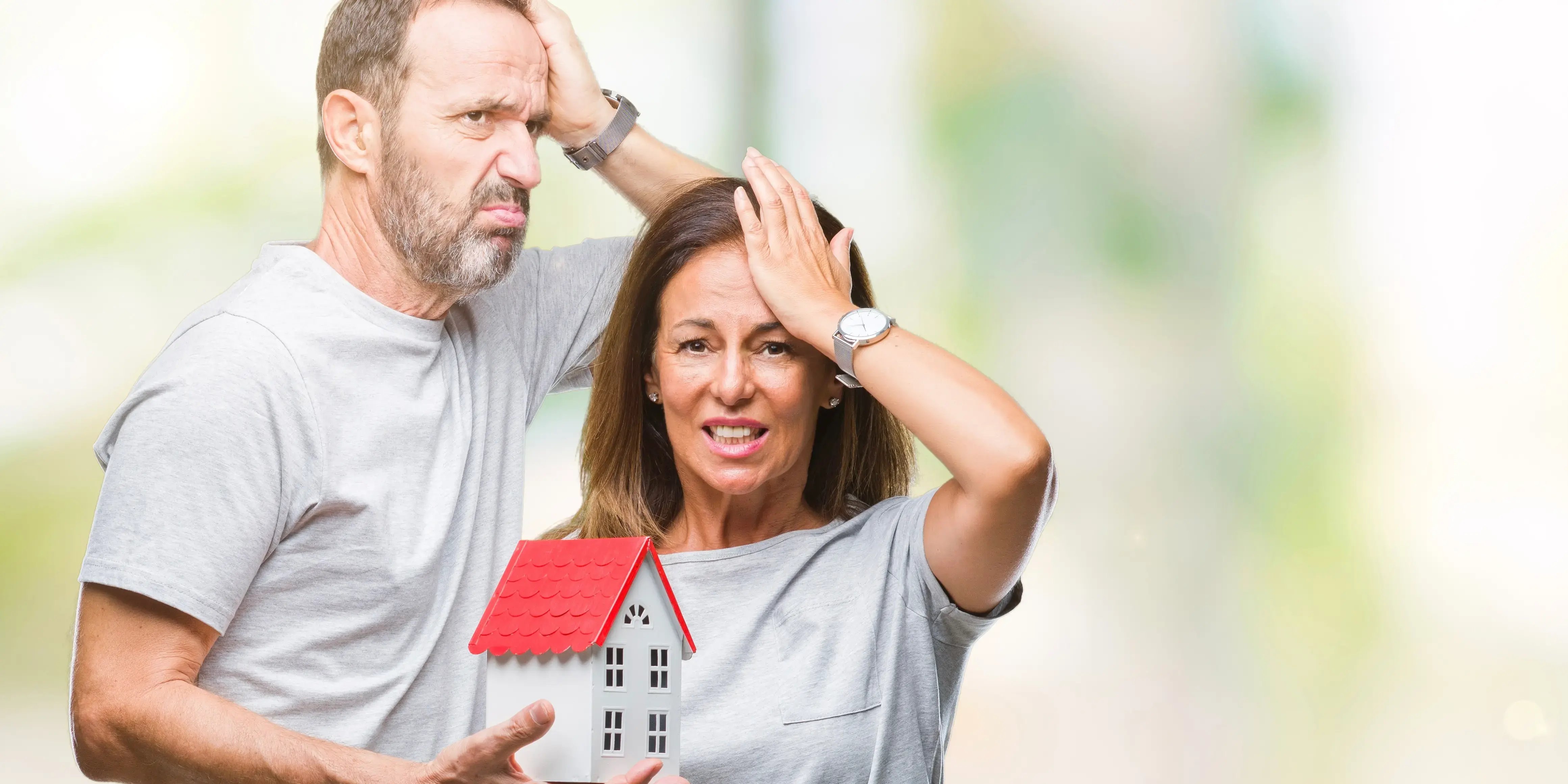 Pareja de edad mediana agarrándose la cabeza pernando en los errores que deben evitar al comprar una casa barata