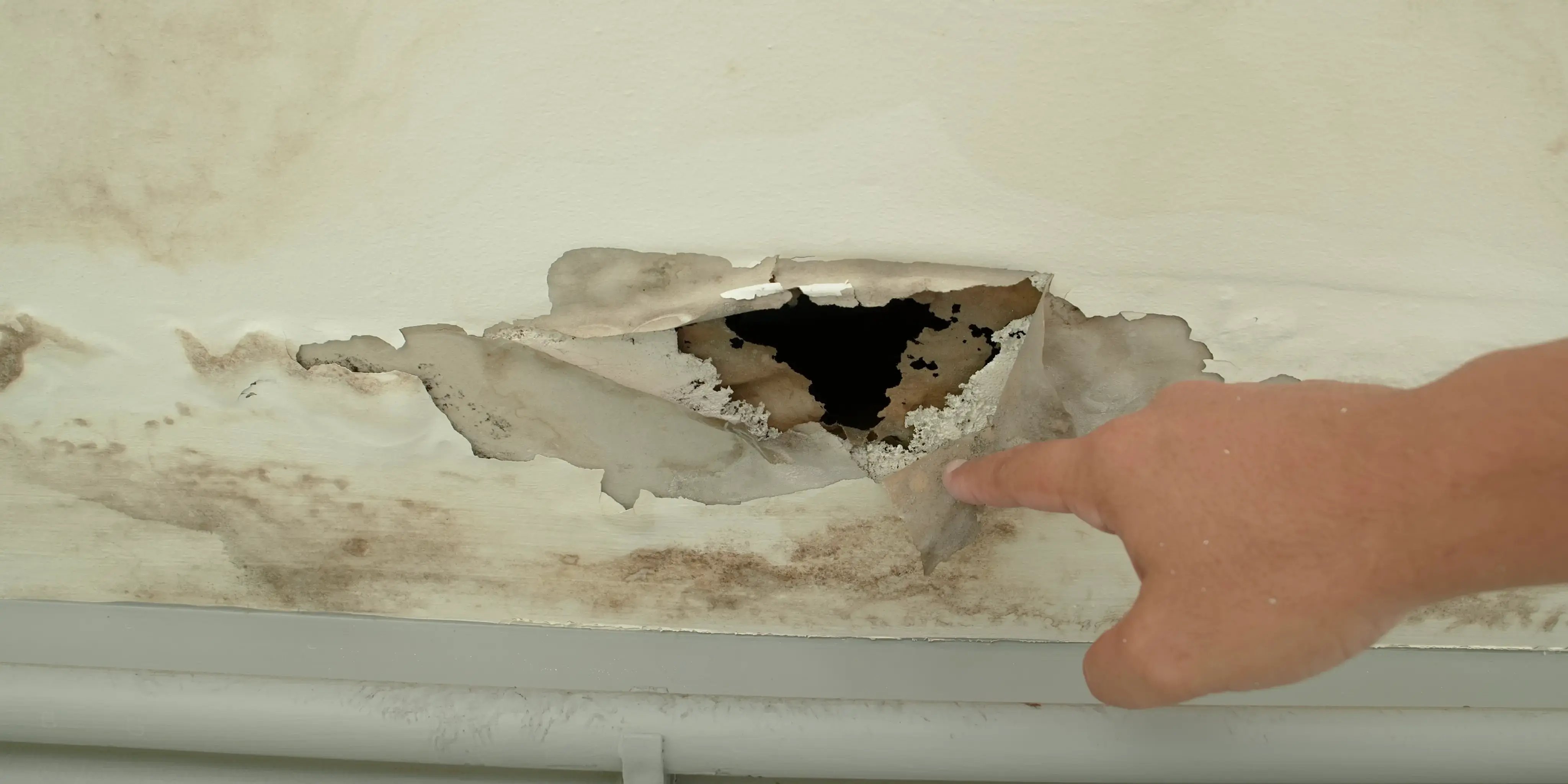 Persona señalando las grietas y humedad de una casa sin mantenimiento