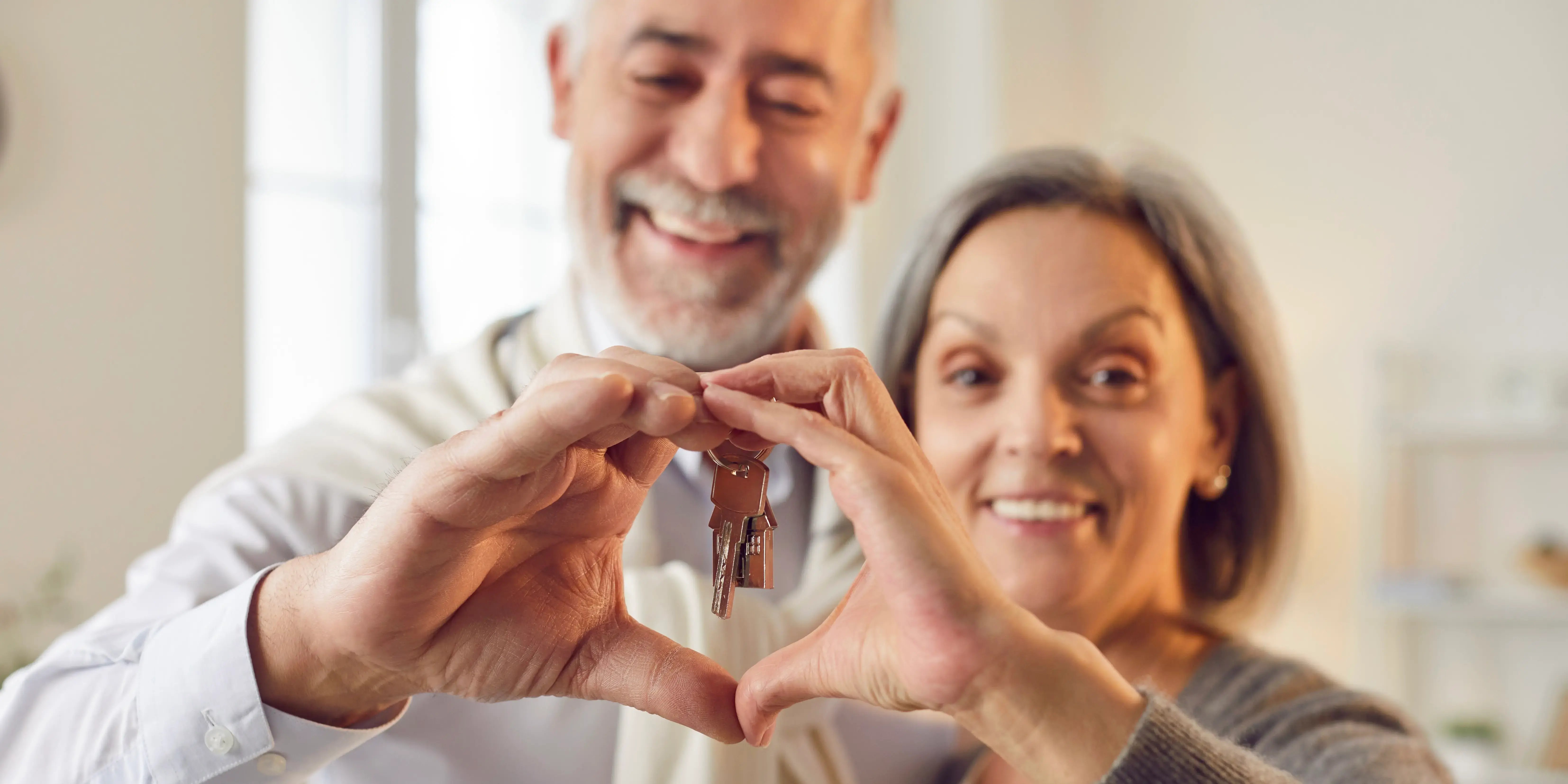 Personas mayores sosteniendo las llaves de su nueva casa que compraron con el crédito hipotecario IMSS