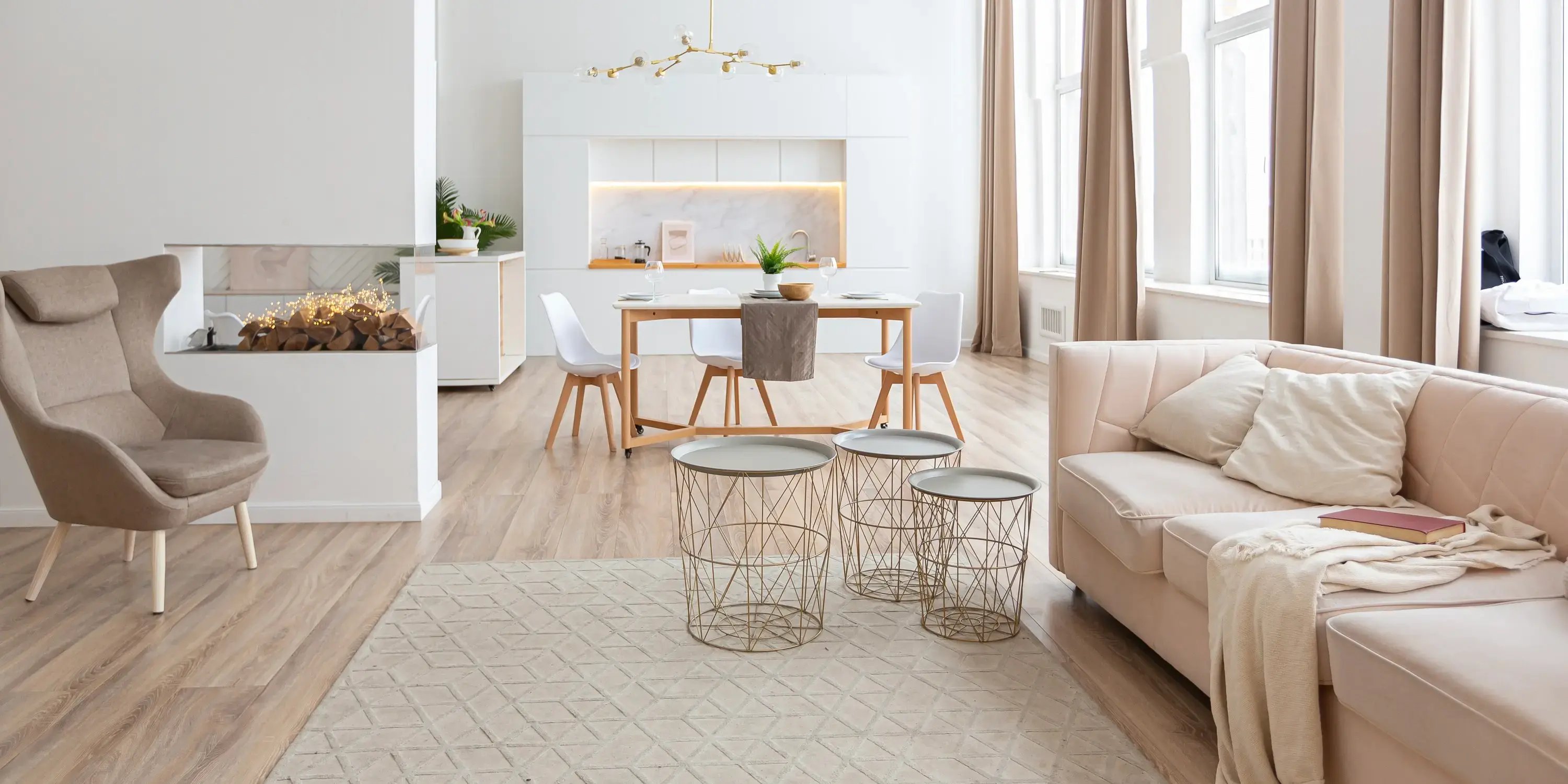 Sala, cocina y comedor de diseño de interiores de estilo escandinavo con colores cálidos en blanco y beige pastel y mobiliario moderno en la zona de estar y detalles modernos con luces led en la zona de cocina