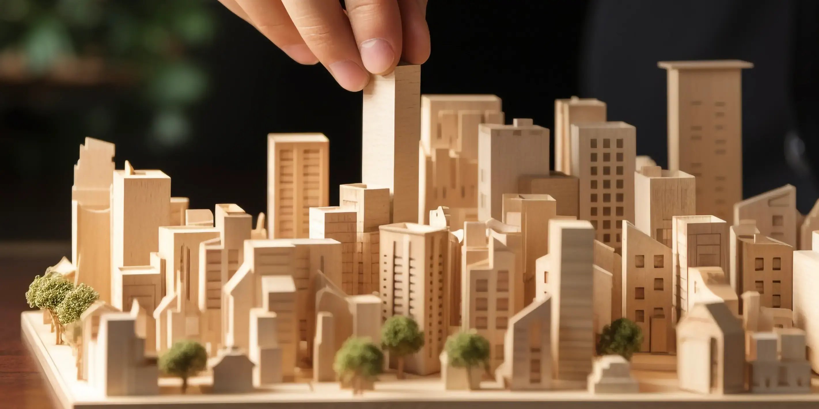 Tipos y estilos de vivienda, con una mano sosteniendo una maqueta con edificios y casas de madera de una maqueta