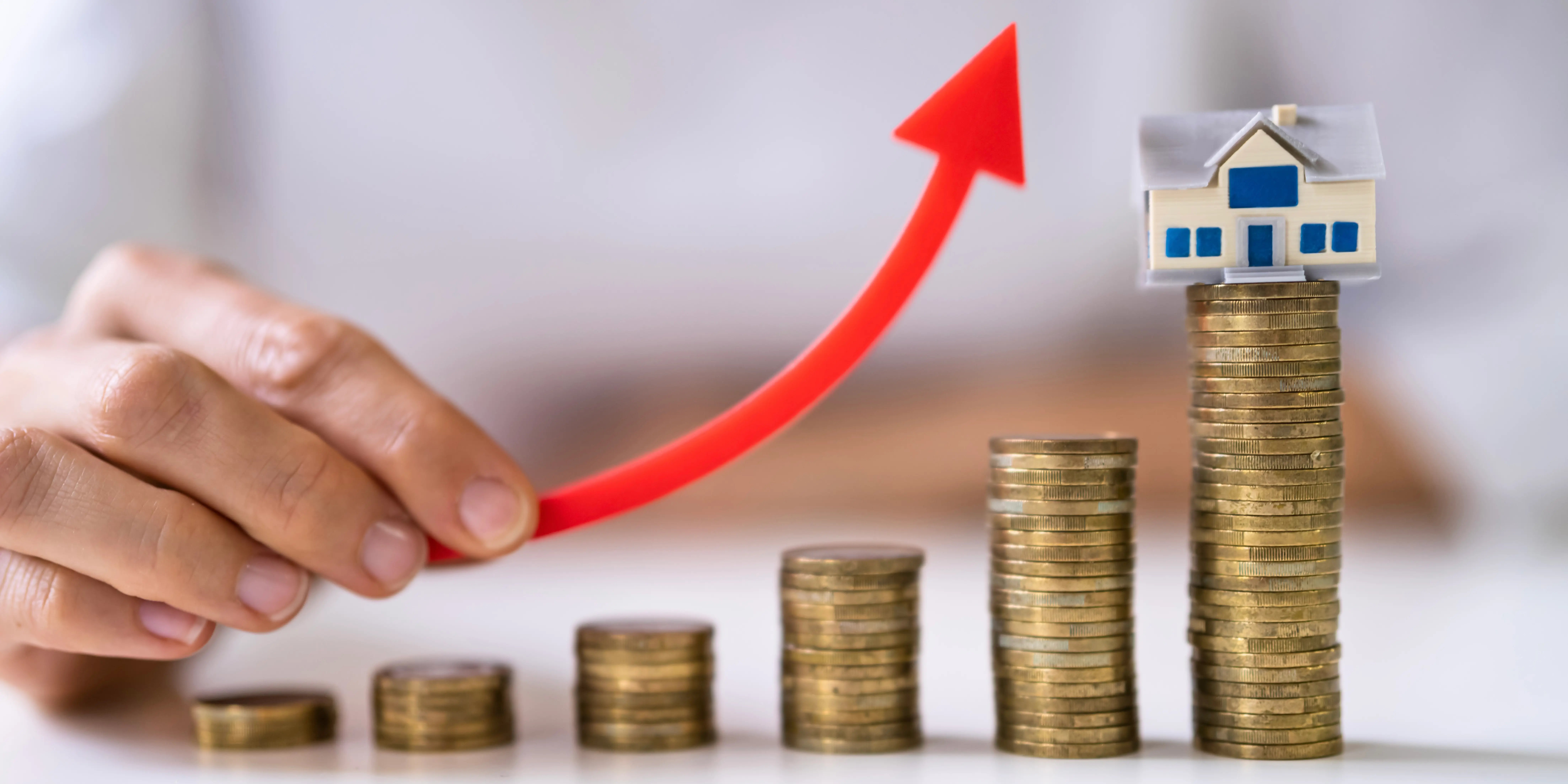 Torres de monedas que van en incremento y la última torre tiene una casa de madera encima representando mayor plusvalía