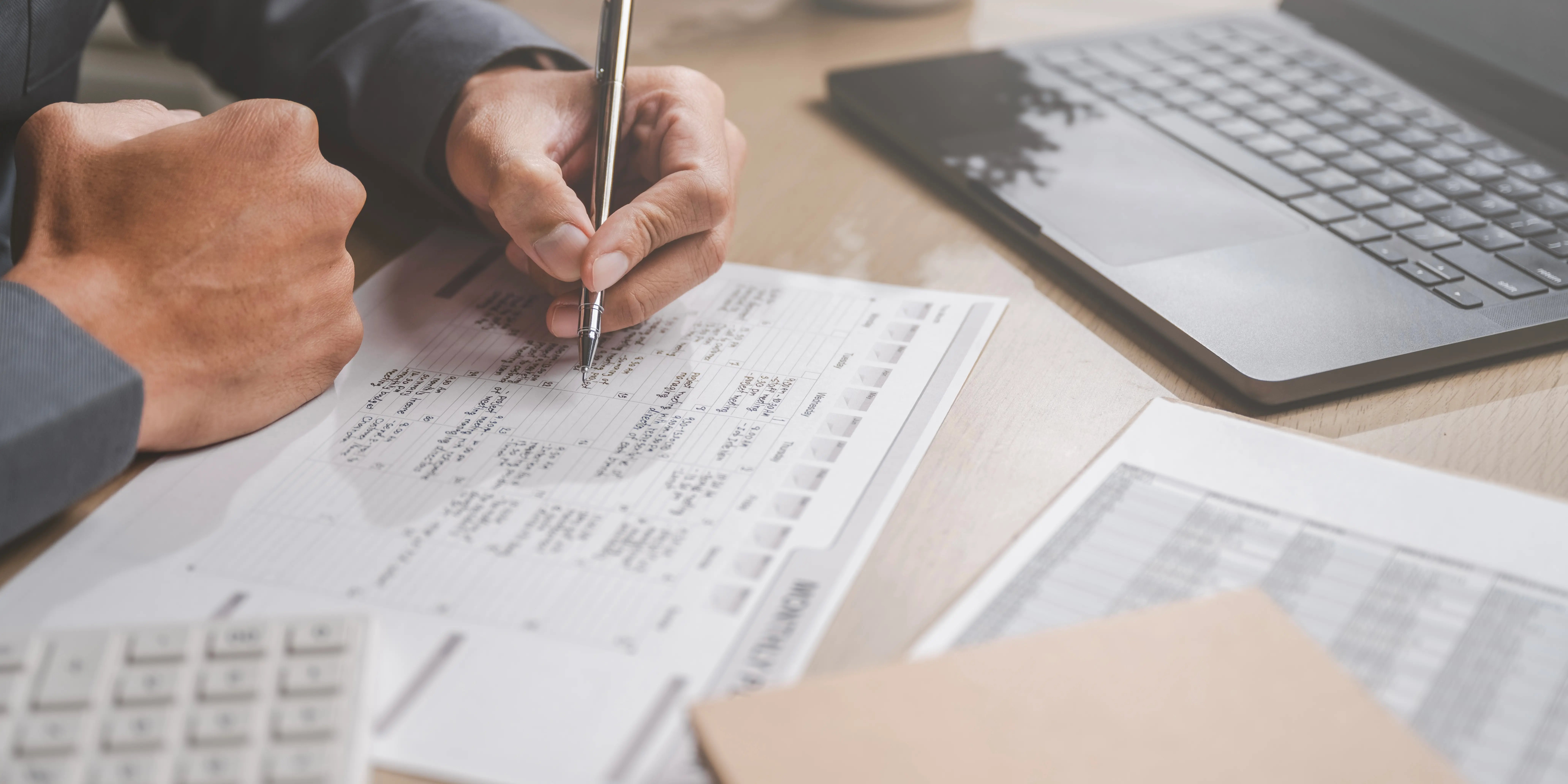 Un hombre está escribiendo en un pedazo de papel con un bolígrafo calculando cuánto va a pagar con una tasa de interés fija