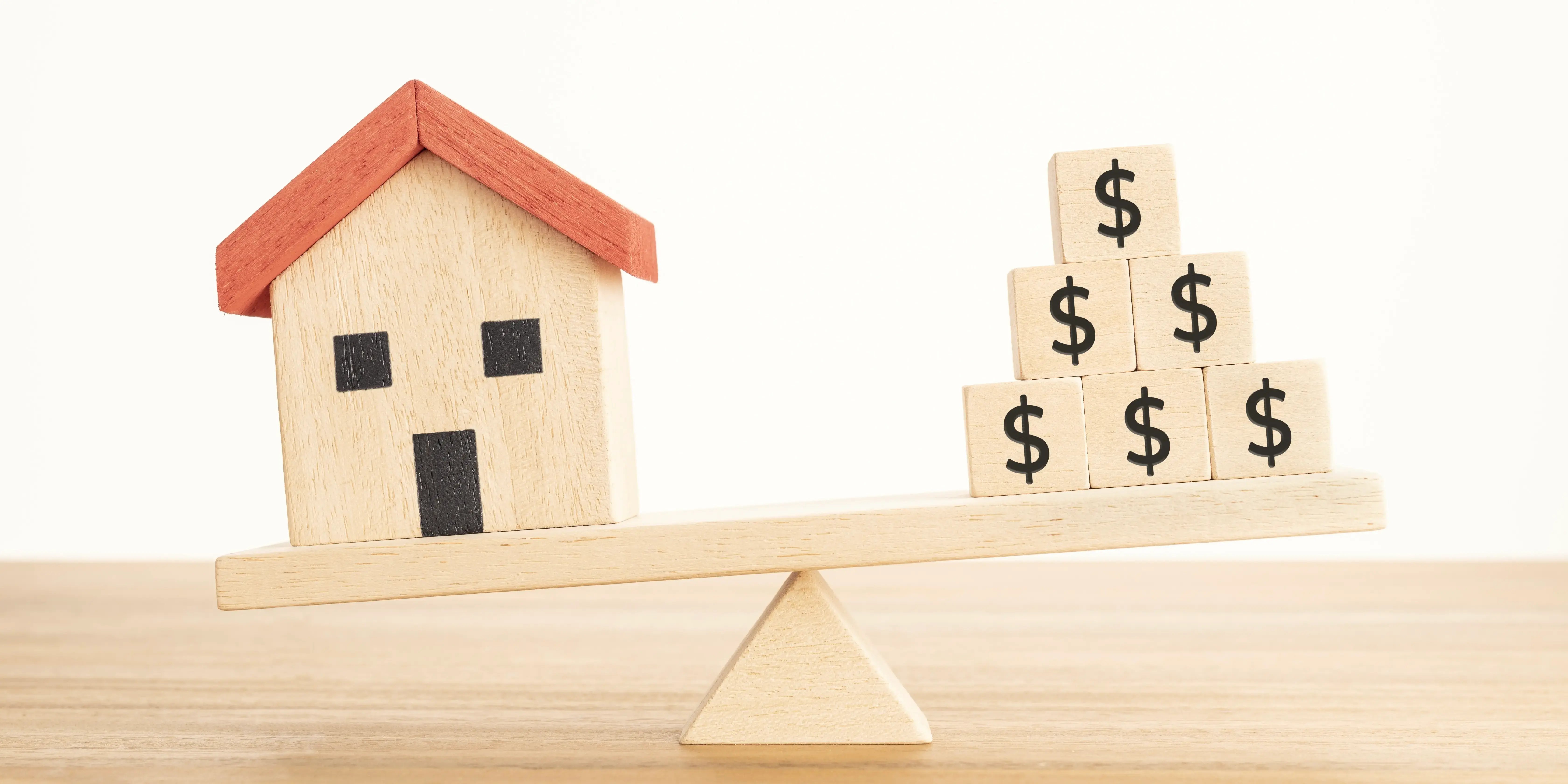 Una balanza en donde del lado izquierdo está una casa de madera y del lado derecho unos cubos con el signo de pesos nivelando el poder adquisitivo para compar una casa