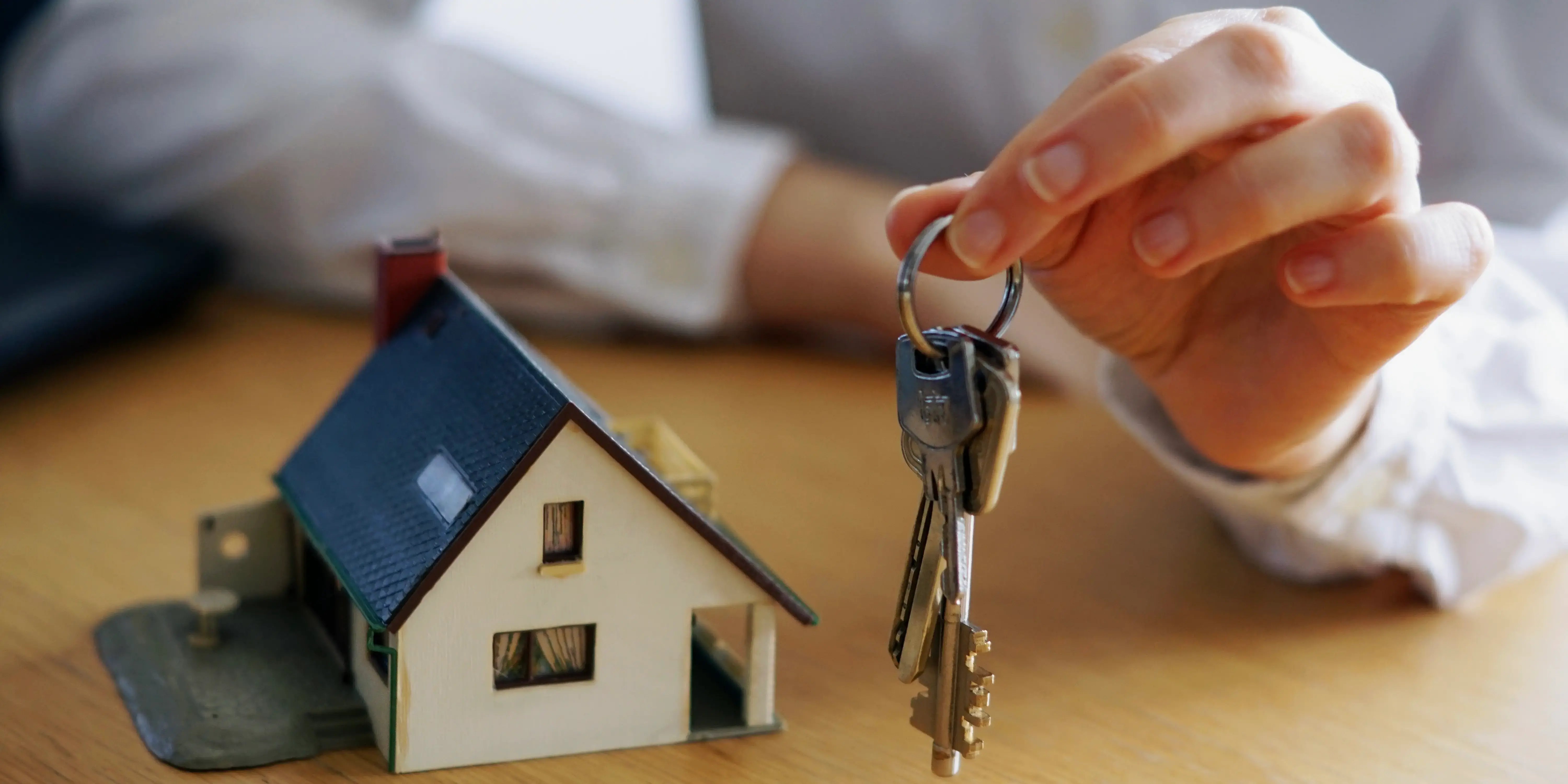 Manos sosteniendo llaves de casa. Inmobiliaria reconocida.