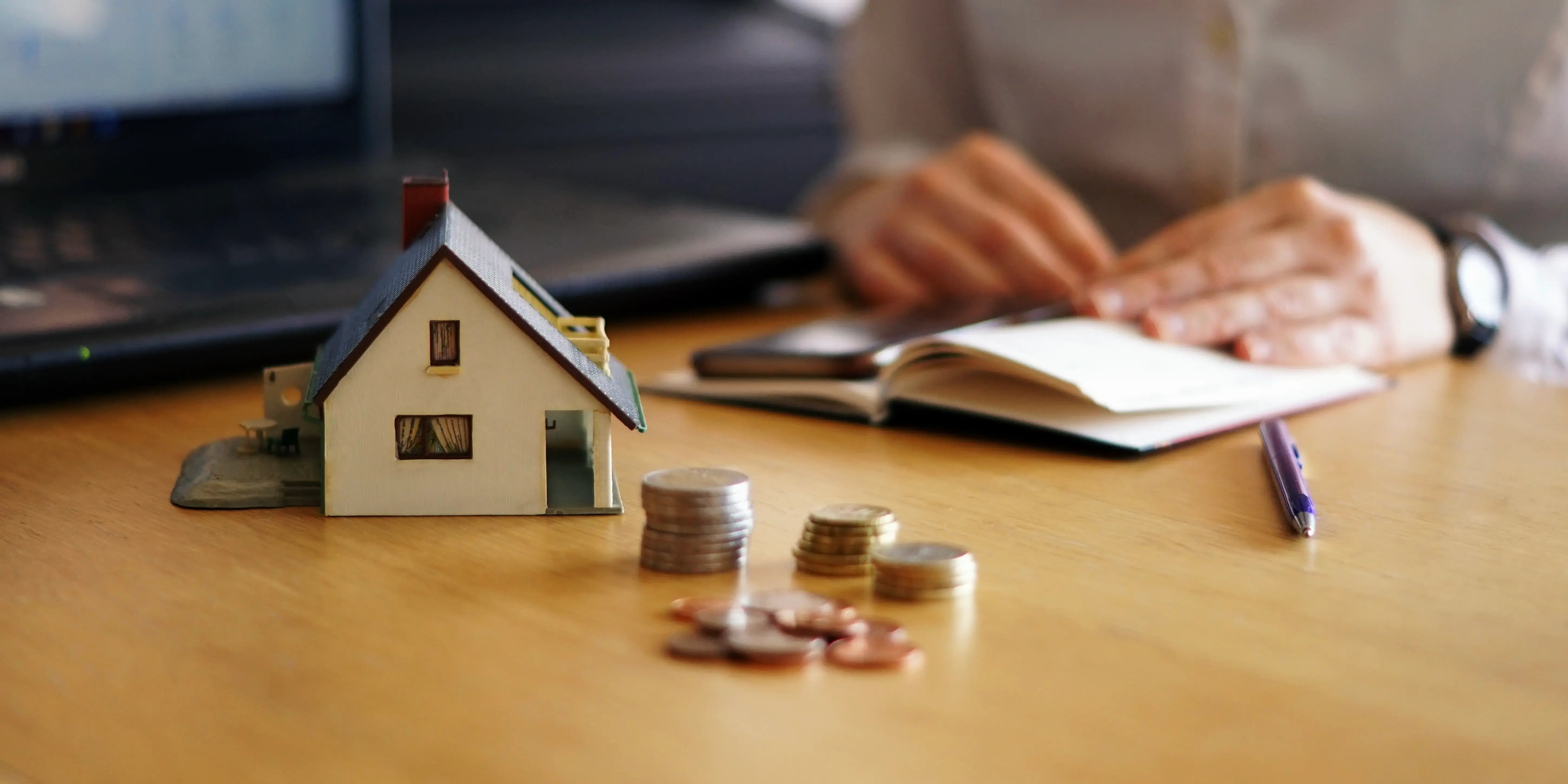 Casa con monedas y una libreta al fondo. Infonavit Total