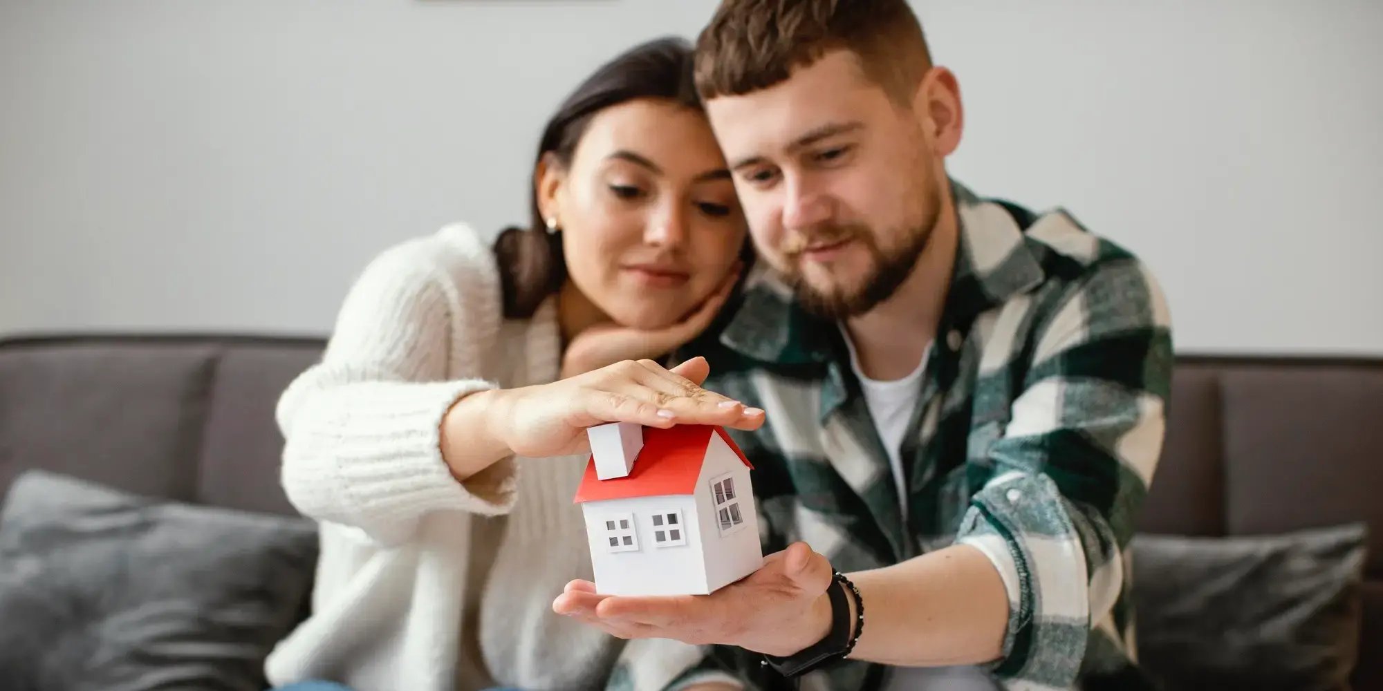 Pareja sosteniendo con las manos una casa. Listo para comprar una casa