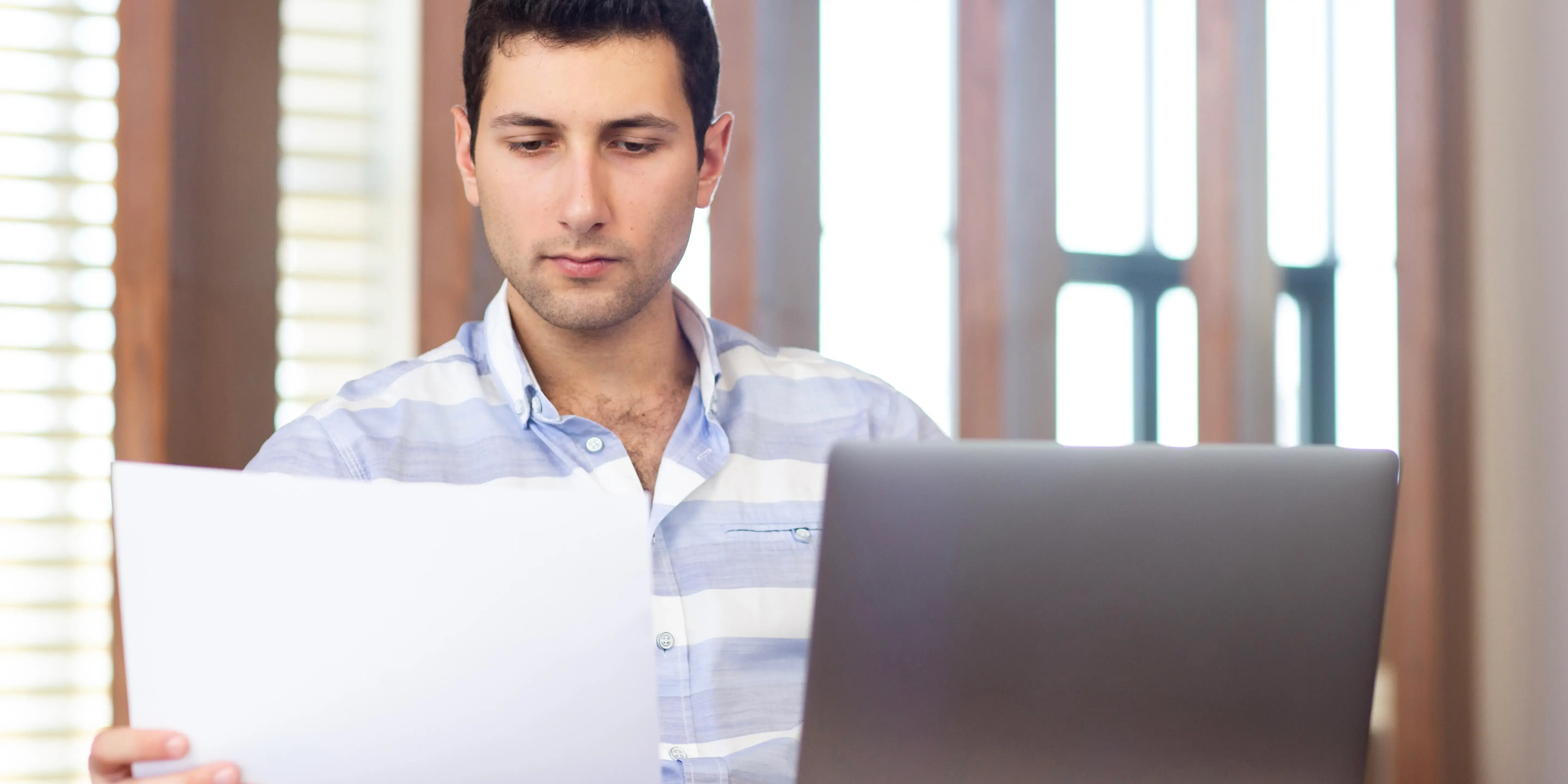 Hombre en computadora, sosteniendo una hoja. constancia no derechohabiente issste