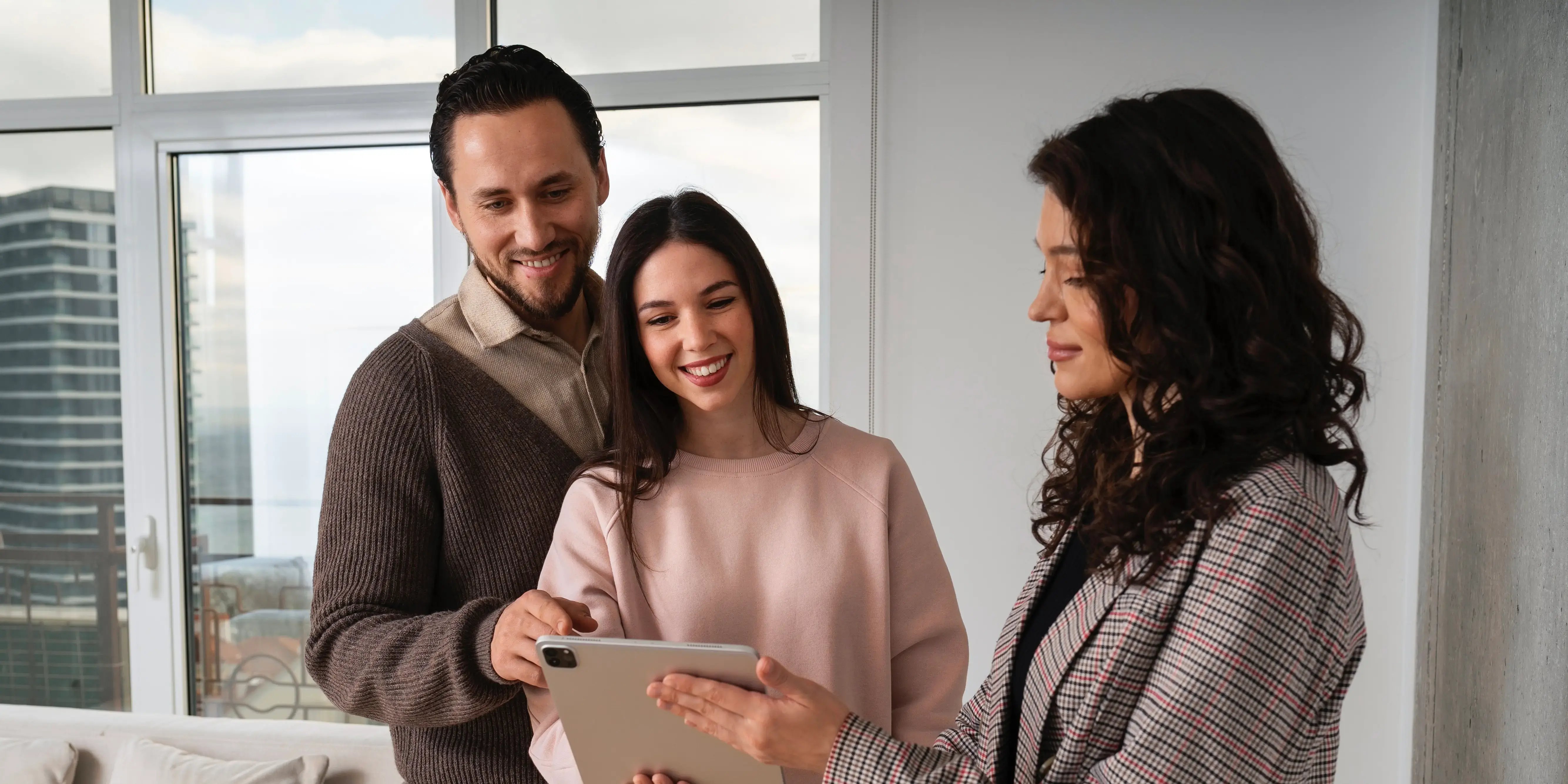 Bróker con table y pareja en edificio. Bróker inmobiliario
