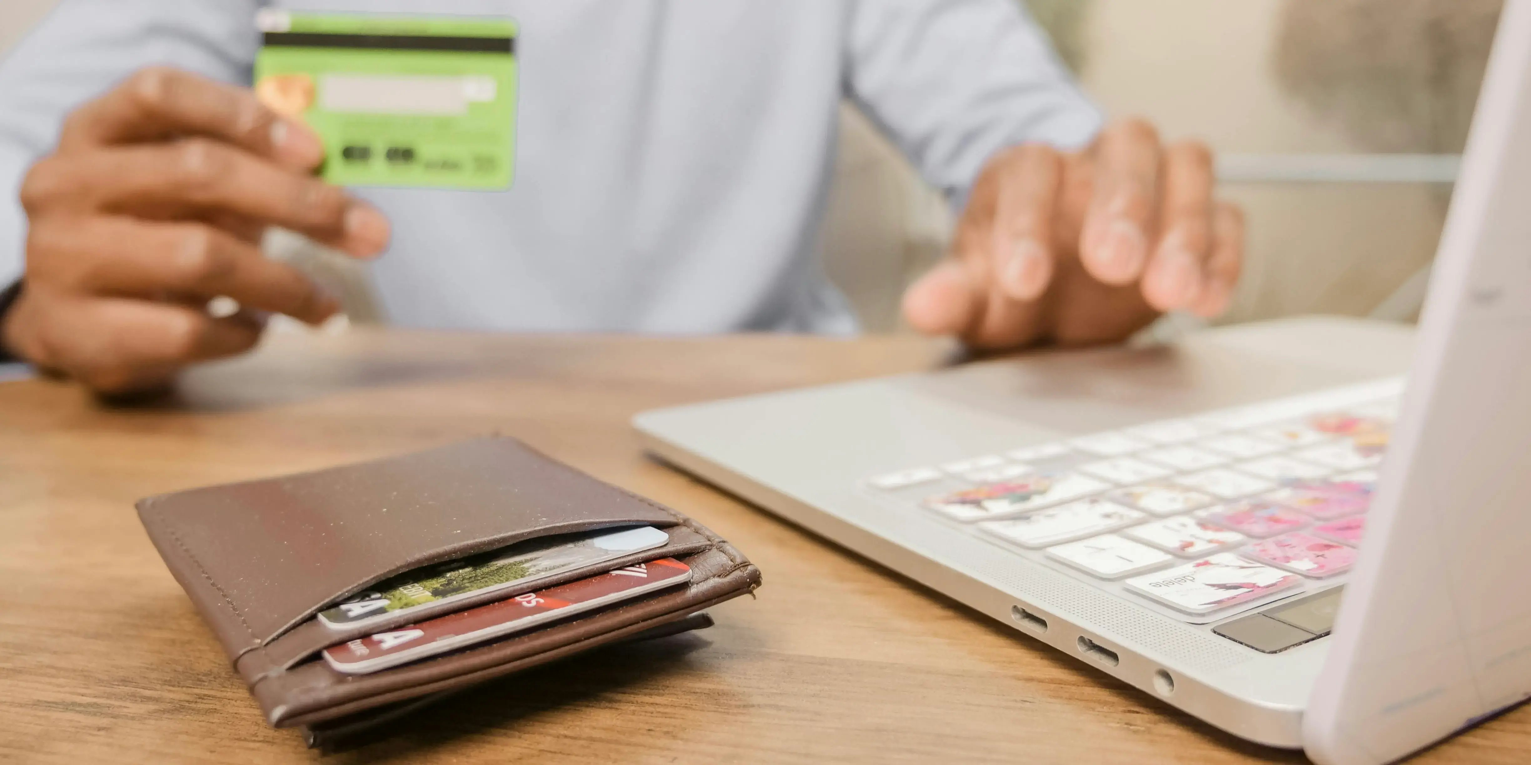 Hombre en computadora pagando tarjeta de crédito. Mejora tu puntaje crediticio