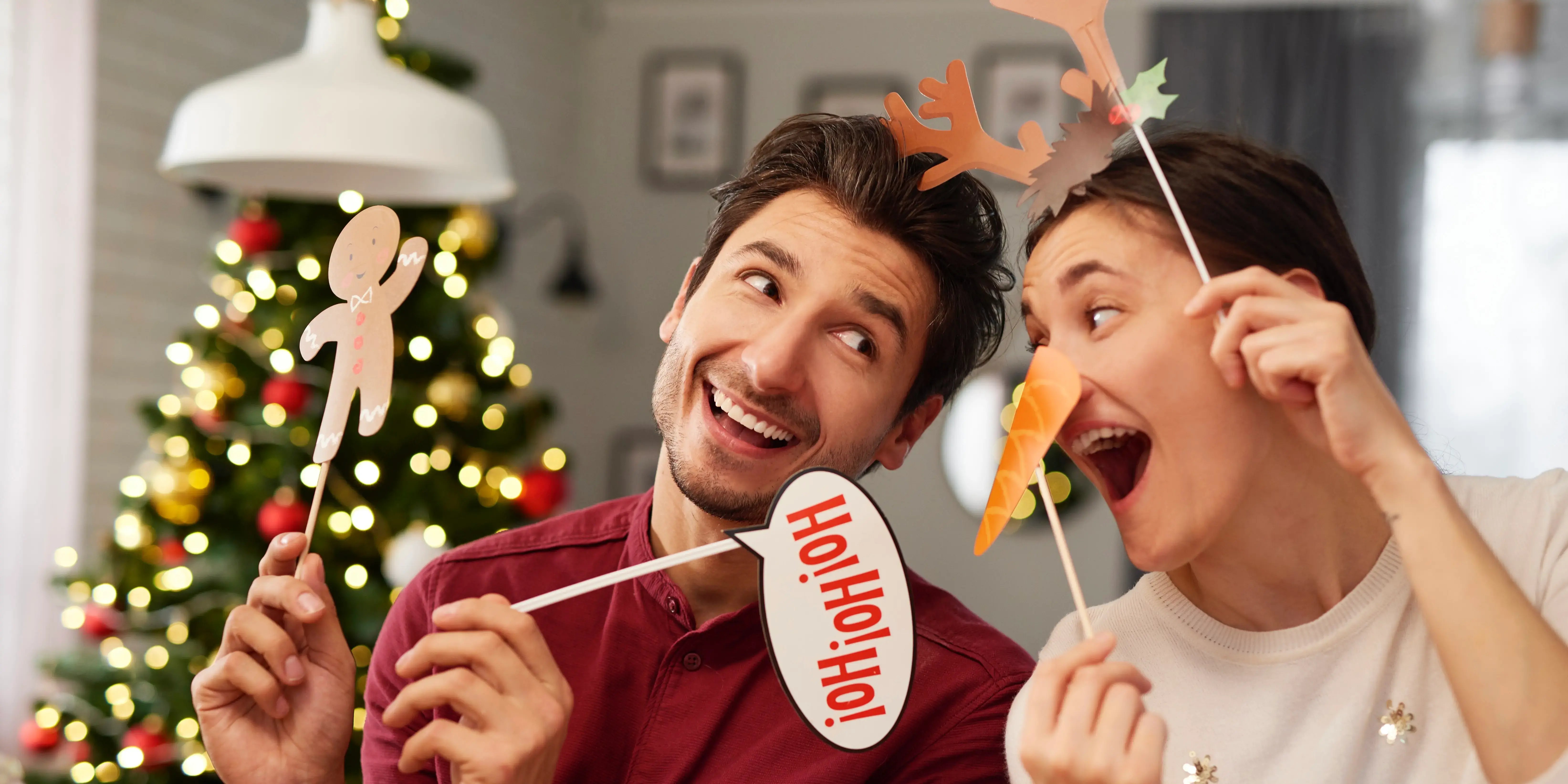 Pareja con letreros de navidad y un árbol decorado al fondo.Navidad inolvidable