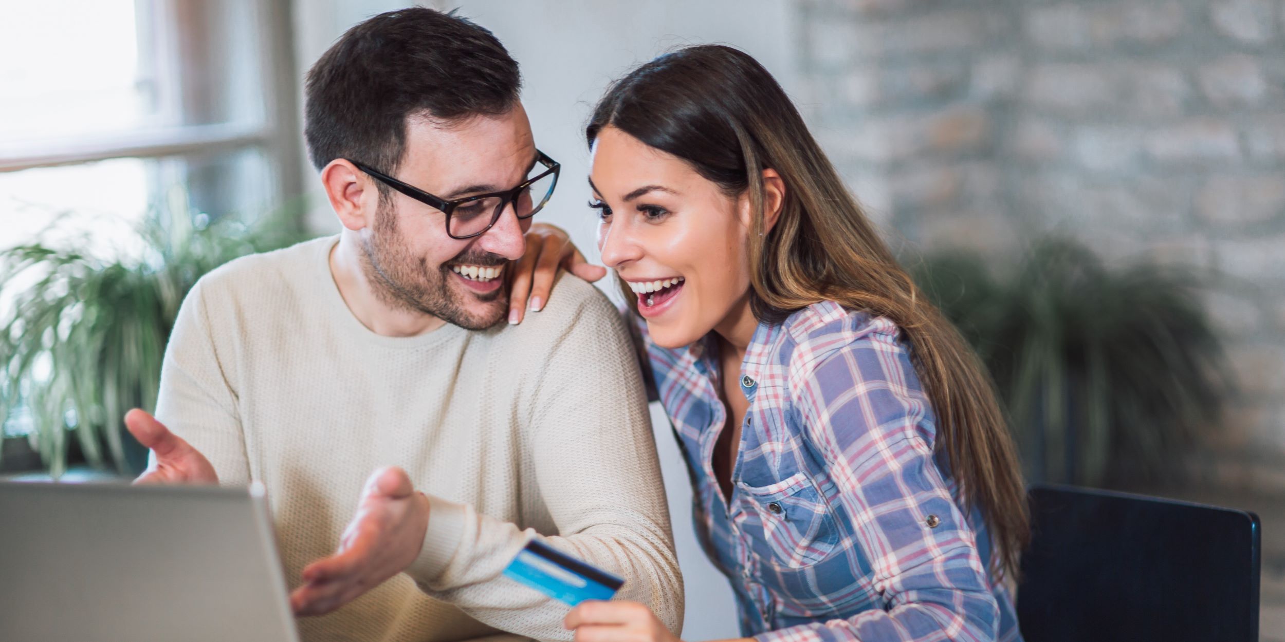 Beneficios de invertir en departamentos o casas. Una pareja adulta joven está viendo opciones en internet para comprar una casa o departamento.