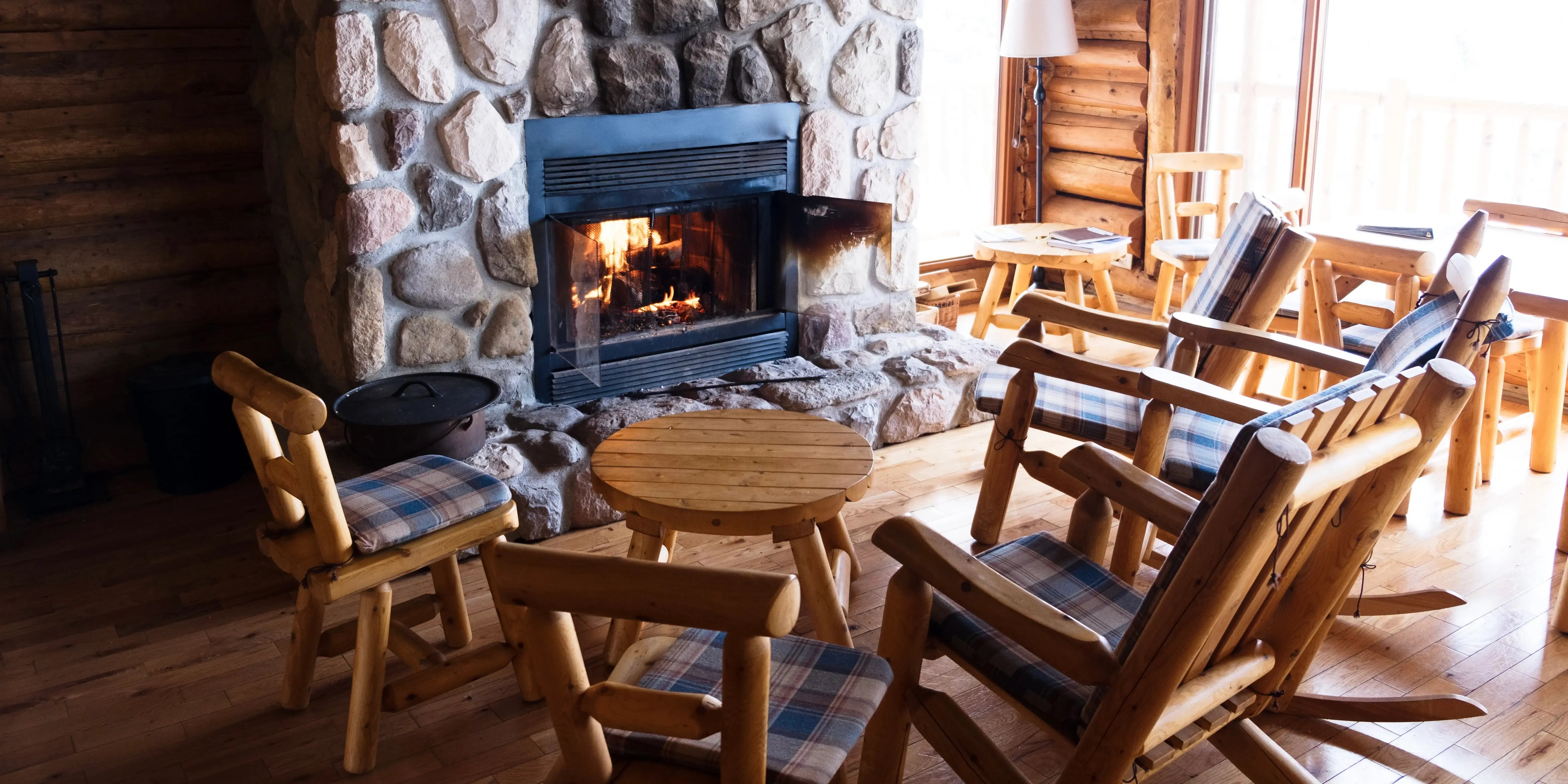 Pared de piedra, con piso de madera y sillas de madera. Casa estilo campo