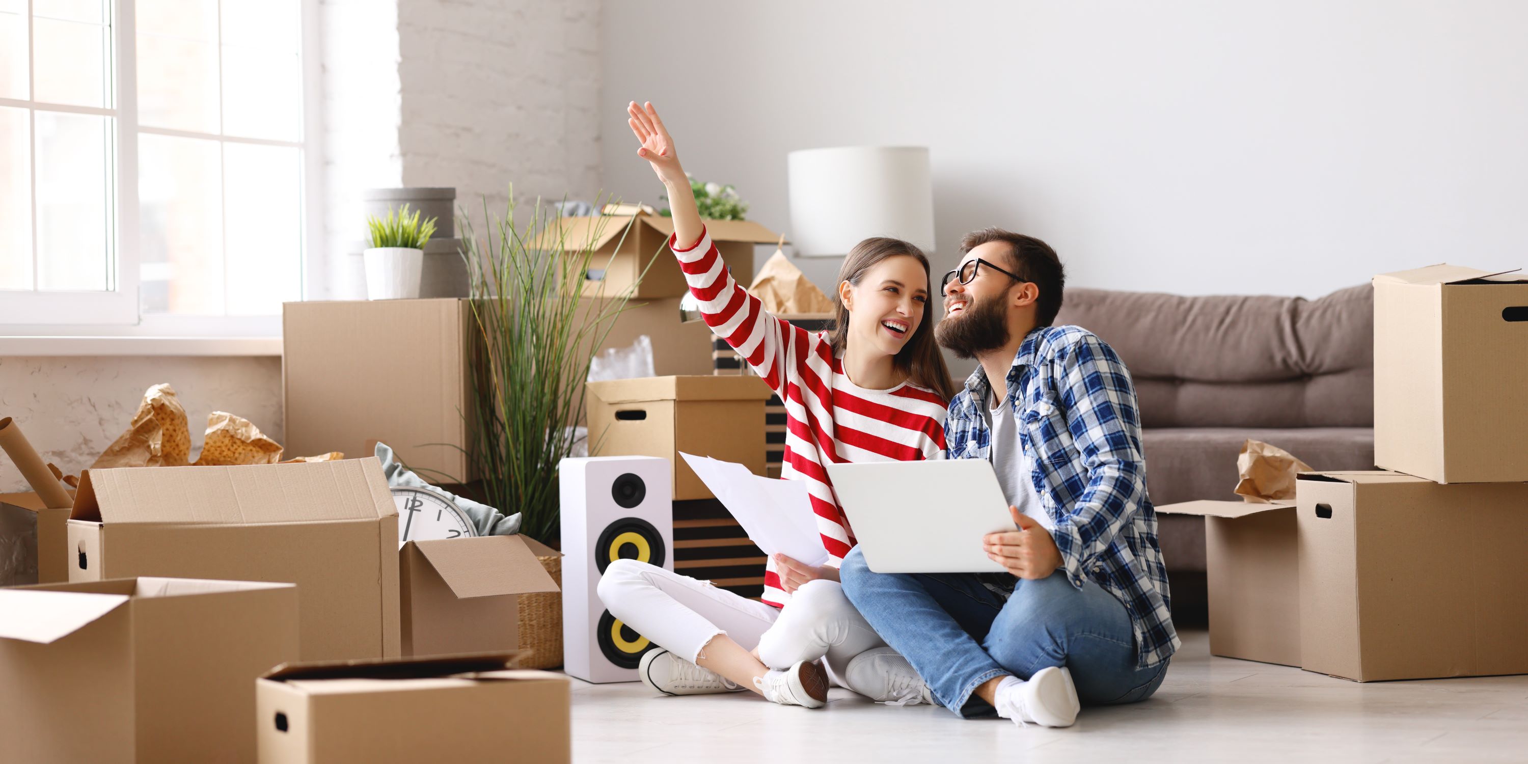 Consejos para invertir en bienes raíces si eres Milenial. Una pareja de adultos jóvenes están desempacando sus cosas en su nueva casa. Se mudaron.