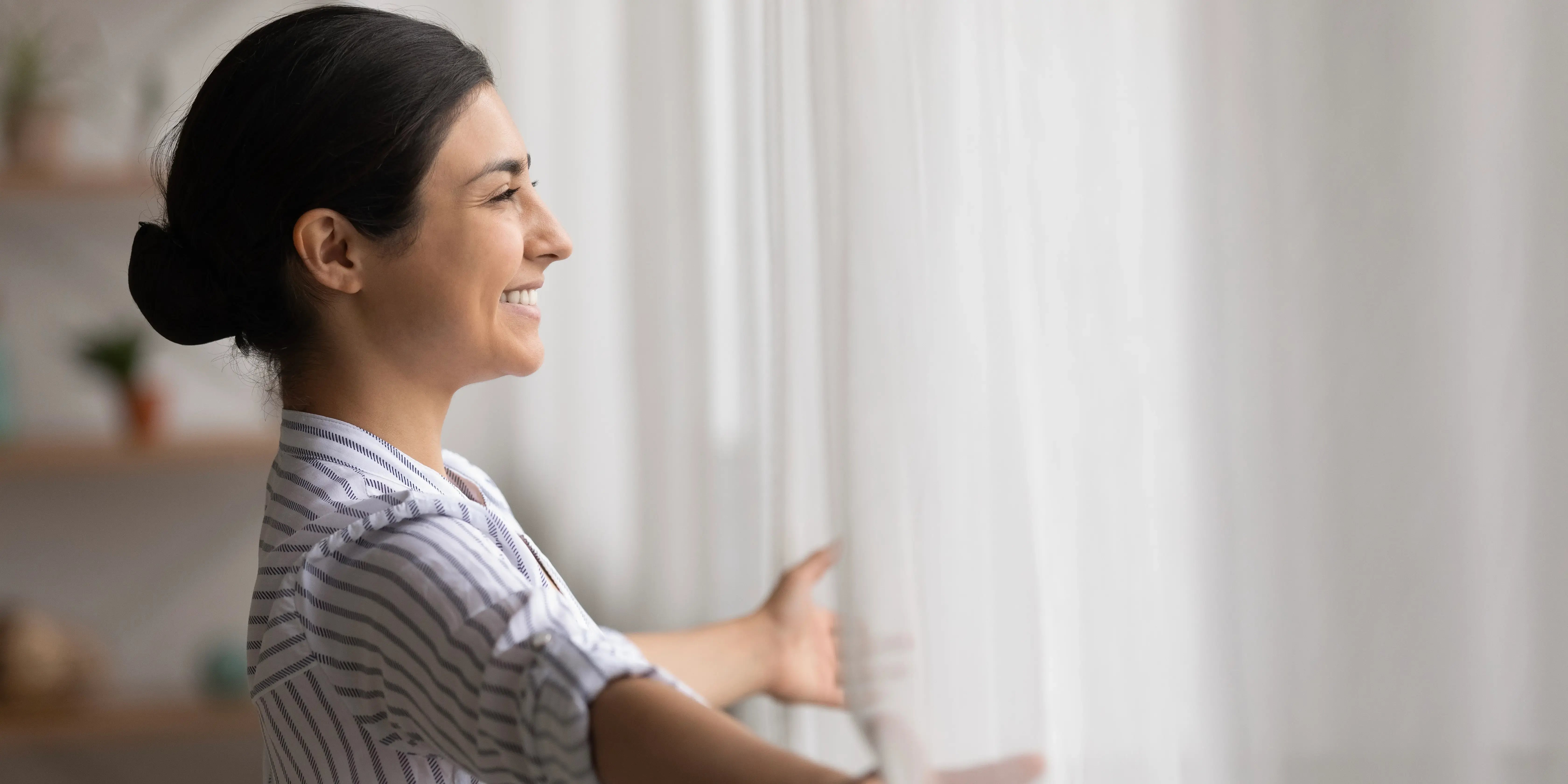 Mujer asomándose por la ventana. Beneficios de vivir en casa duplex