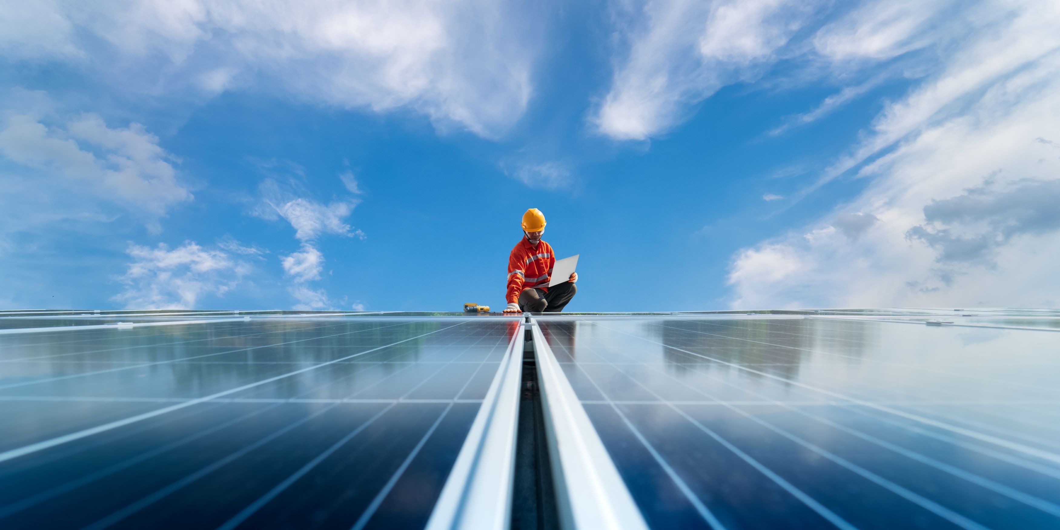 Beneficios de tener un panel solar en tu hogar. Hombre dando mantenimiento a unos paneles solares a cielo abierto.