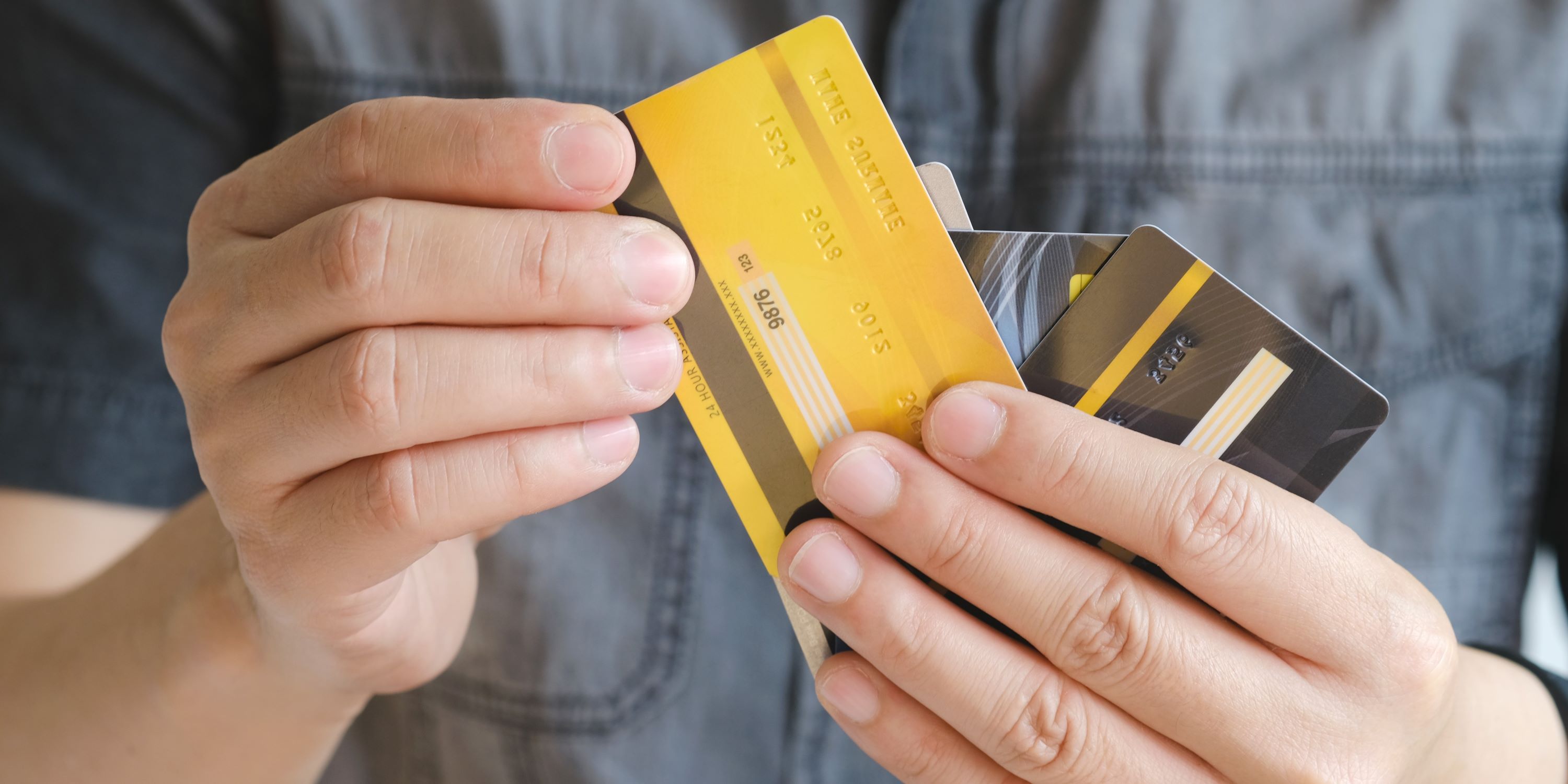 Hombre sostiene varias tarjetas de crédito en la mano. ¿Estará haciendo buen uso de su historial crediticio?