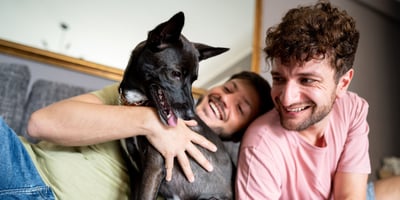 Hipoteca Rosa Infonavit. Pareja joven homosexual con un perro disfrutan su tiempo de calidad con su perro.