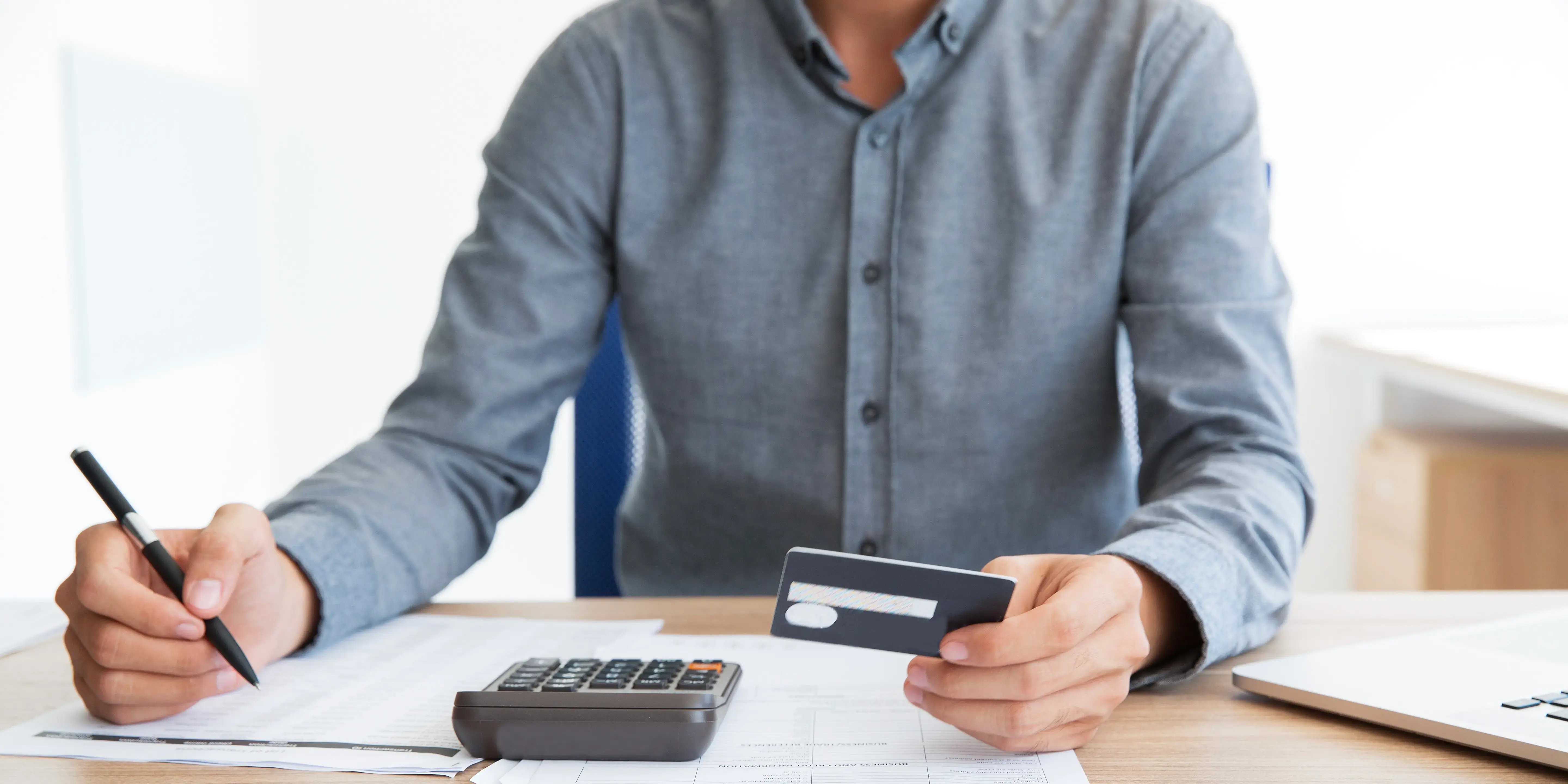 Hombre con tarjeta de crédito y una calculadora. Errores comunes al solicitar un crédito hipotecario