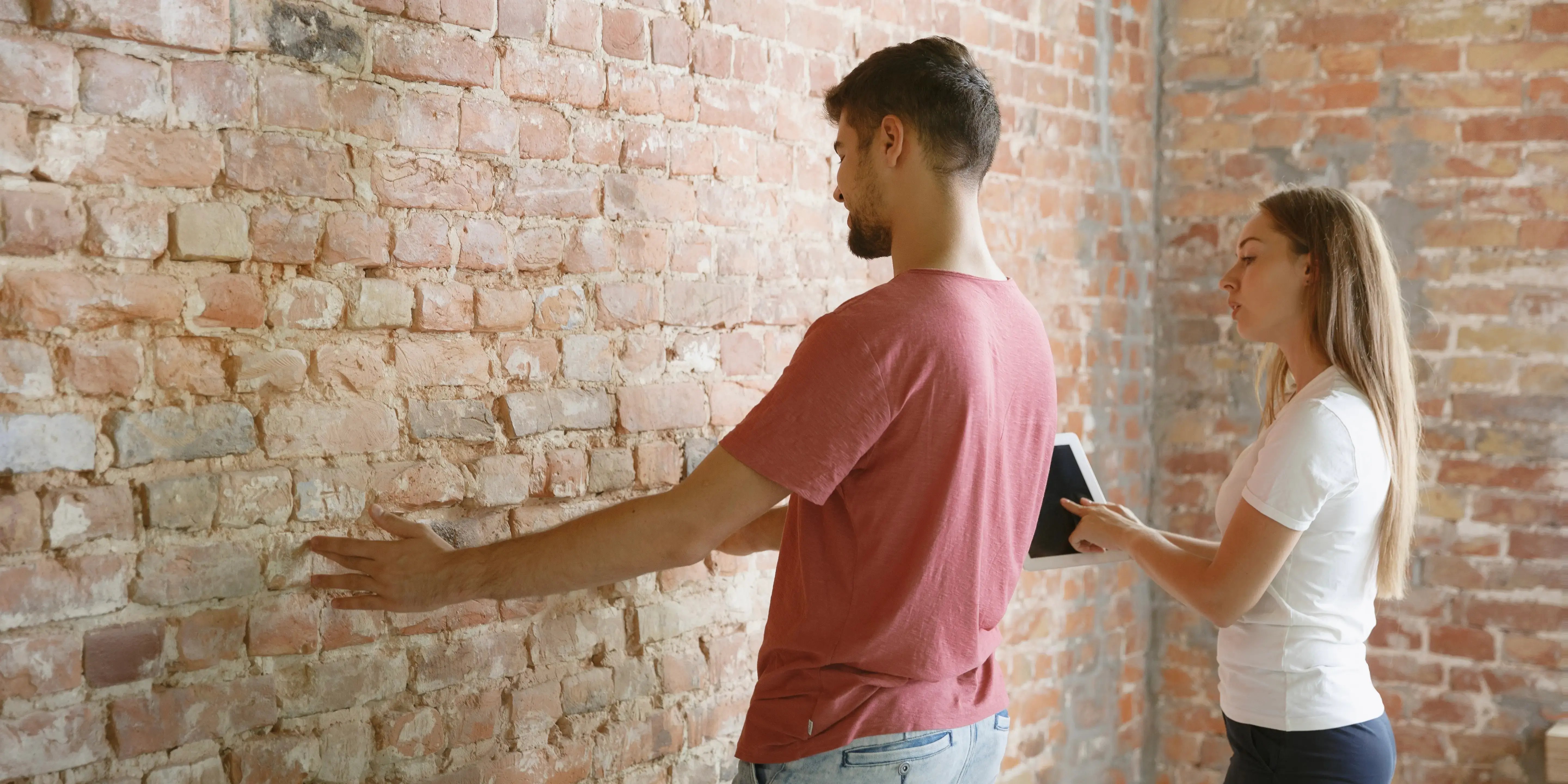 Pareja viendo pared de ladrillo. Problemas estructurales